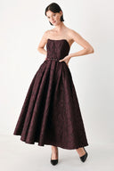A woman models a strapless burgundy A-line gown with a textured jacquard bodice and a matching beaded waistband | FREEMARKET