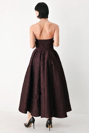 A woman models a strapless burgundy A-line gown with a textured jacquard bodice and a matching beaded waistband | FREEMARKET