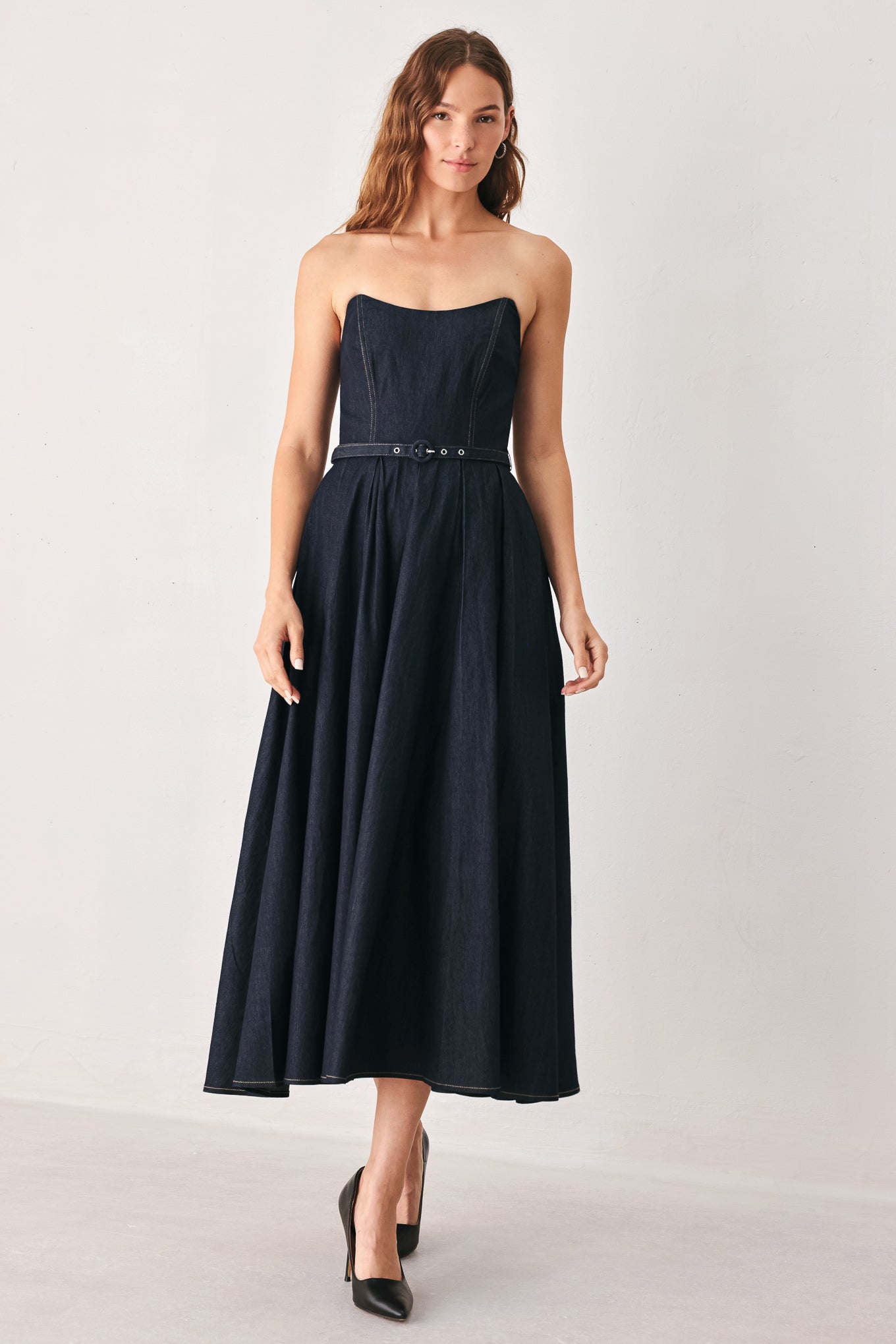 A woman wearing a strapless midi dress in dark navy blue with a matching belt | FREEMARKET