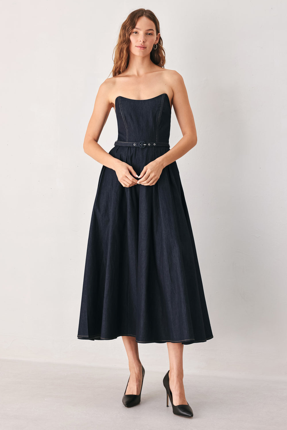 A woman wearing a strapless midi dress in dark navy blue with a matching belt | FREEMARKET