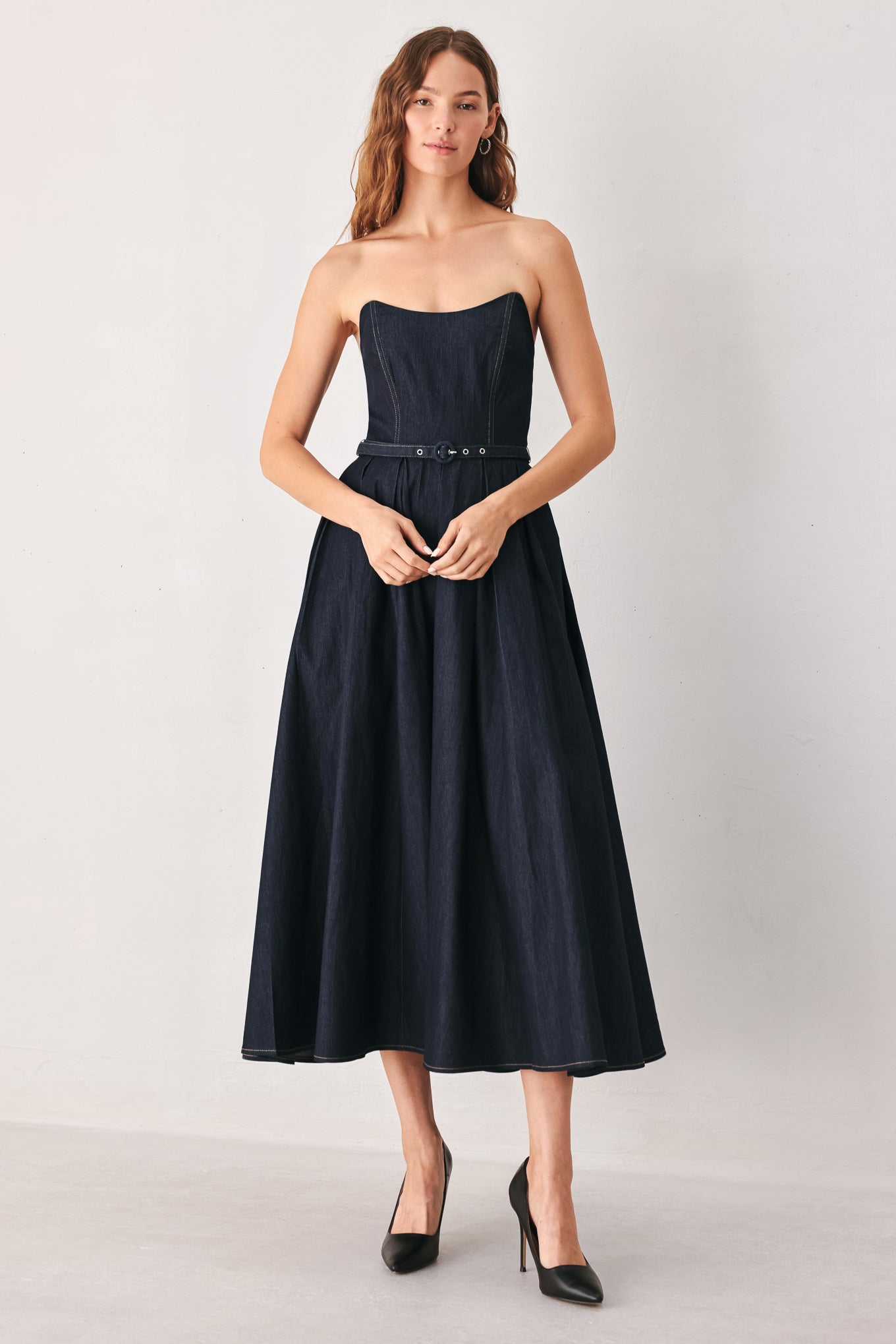 A woman wearing a strapless midi dress in dark navy blue with a matching belt | FREEMARKET
