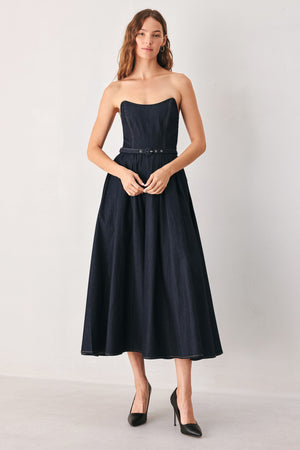 A woman wearing a strapless midi dress in dark navy blue with a matching belt | FREEMARKET