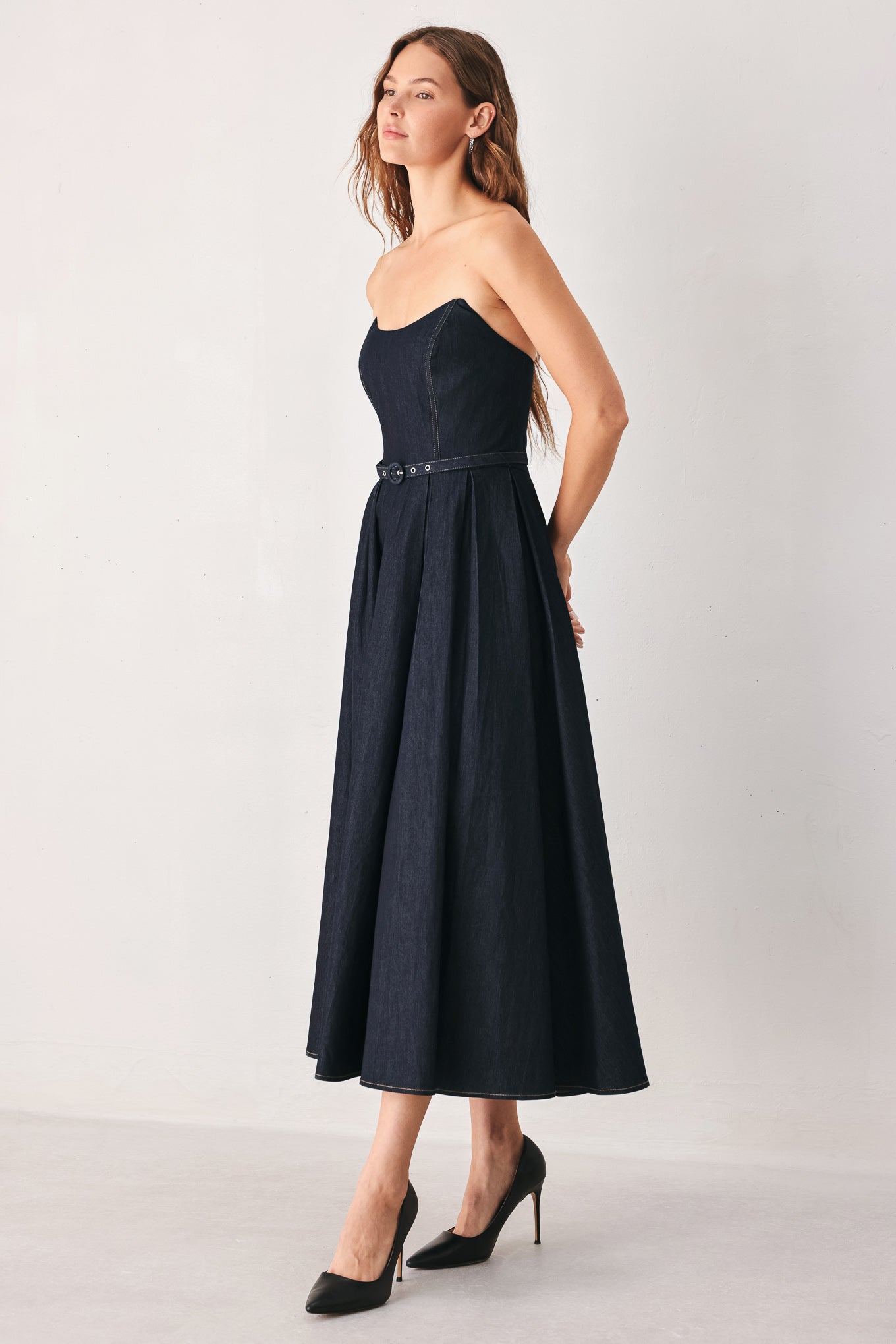 A woman wearing a strapless midi dress in dark navy blue with a matching belt | FREEMARKET