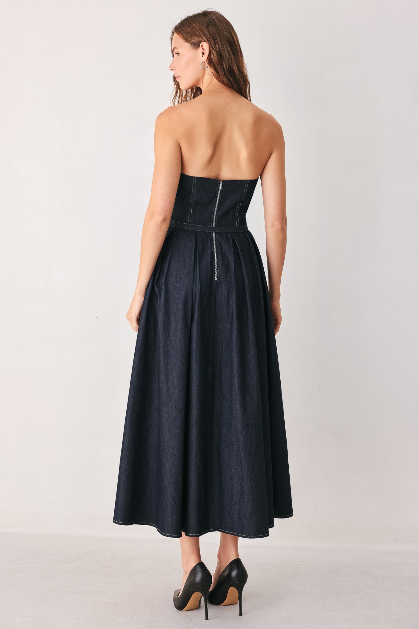 A woman wearing a strapless midi dress in dark navy blue with a matching belt | FREEMARKET