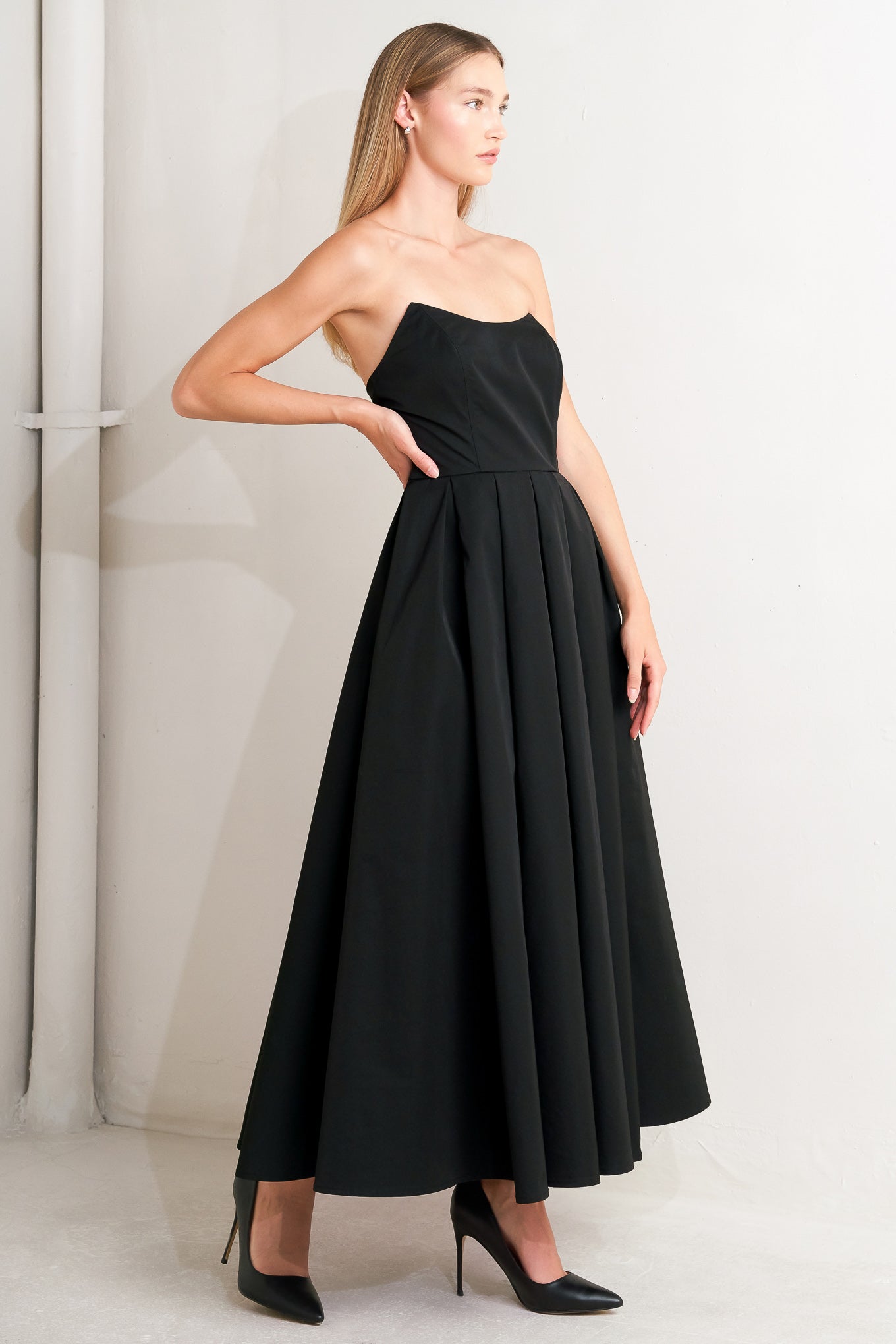 A solid woven midi dress featuring strapless with pointed side neckline, full skirt and back zipper closure