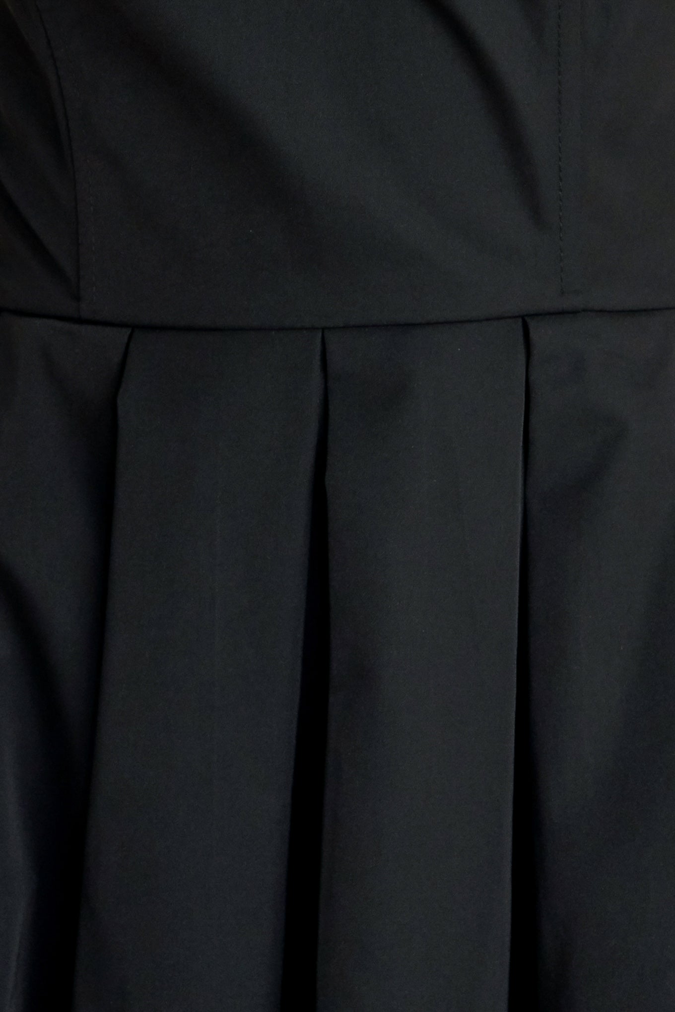 A solid woven midi dress featuring strapless with pointed side neckline, full skirt and back zipper closure
