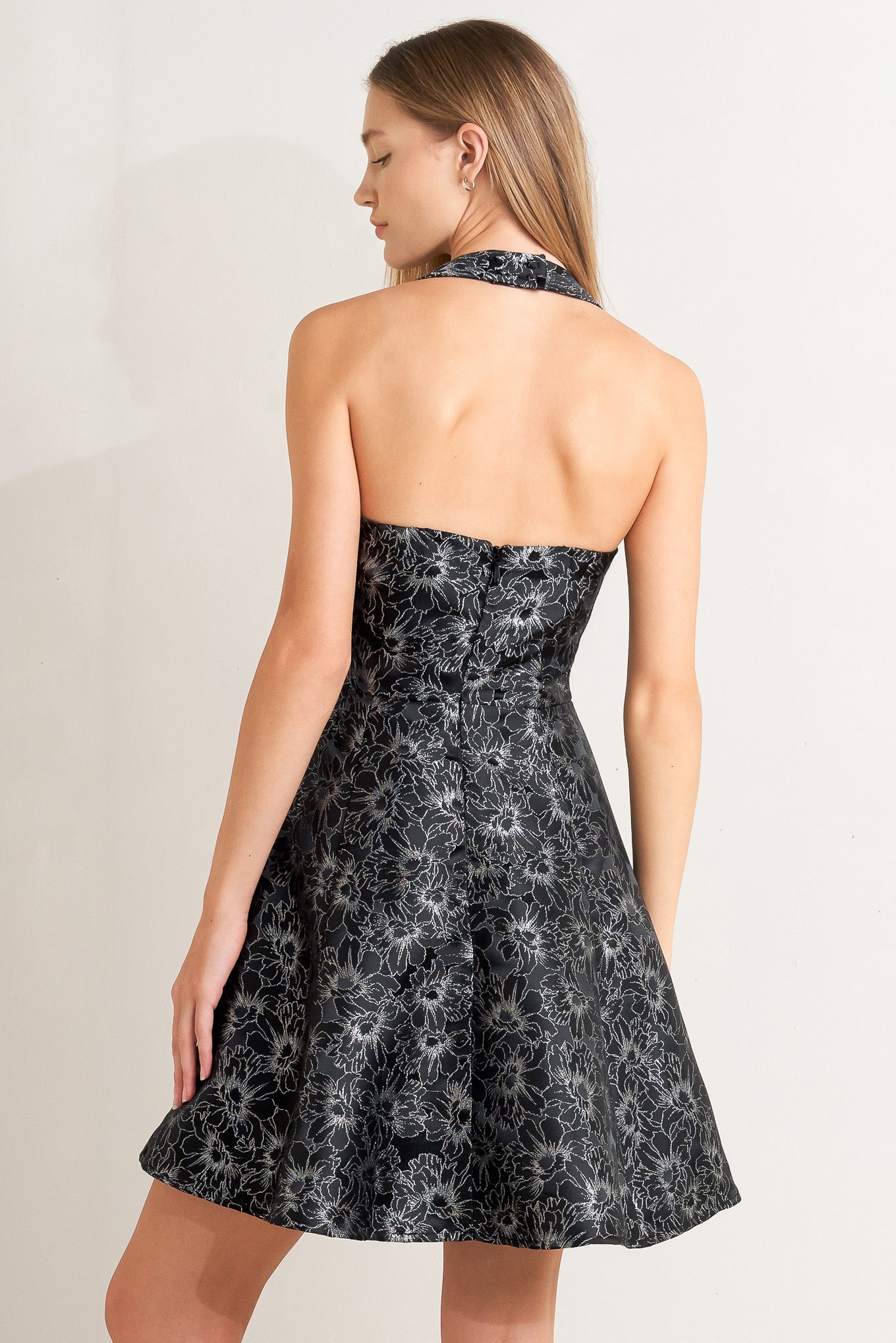 A woven jacquard mini dress featuring halter neckline, circle skirt open back with button and zipper closure