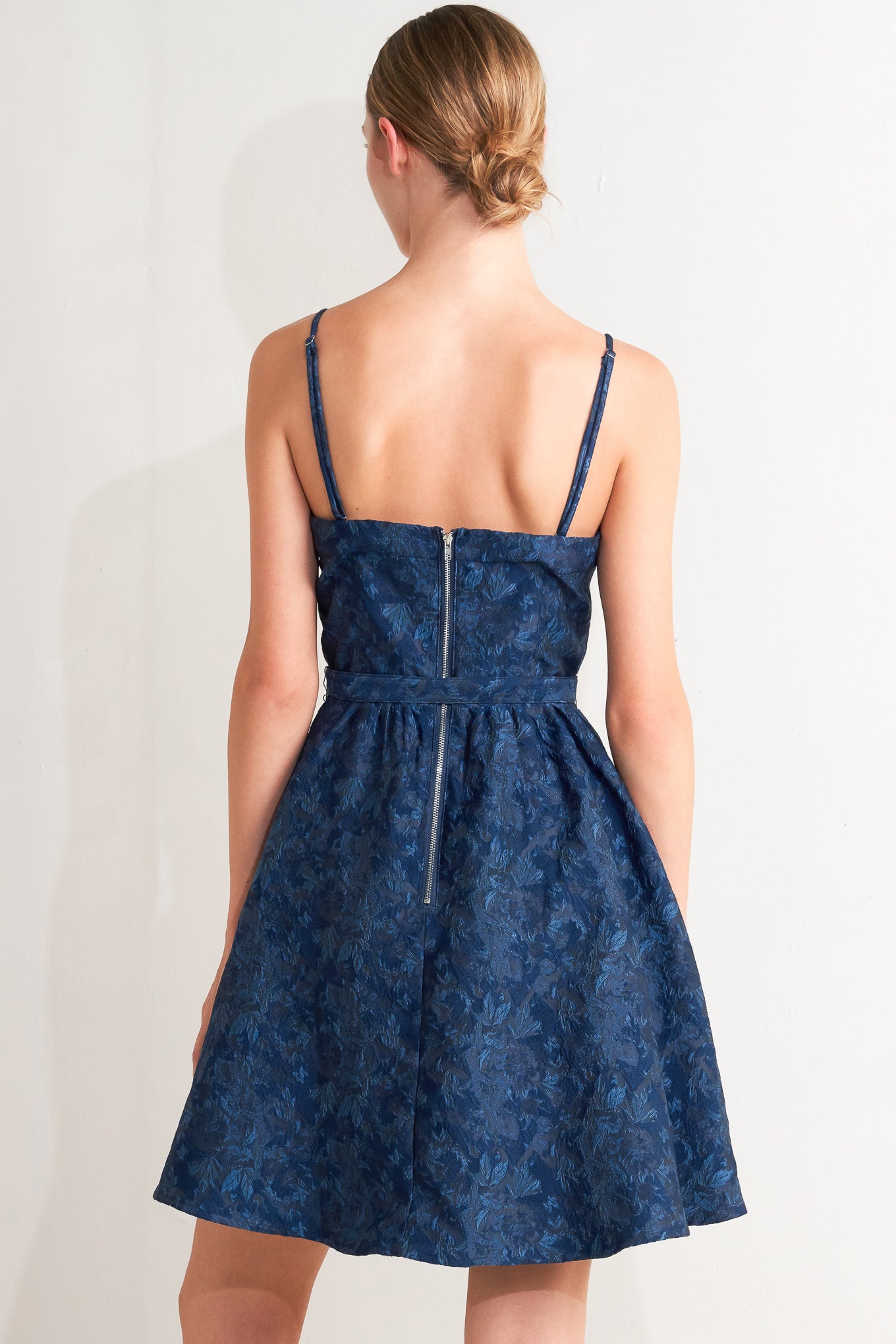 A woven jacquard mini dress featuring bustier top, straps, self belt, full skirt and back zipper closure