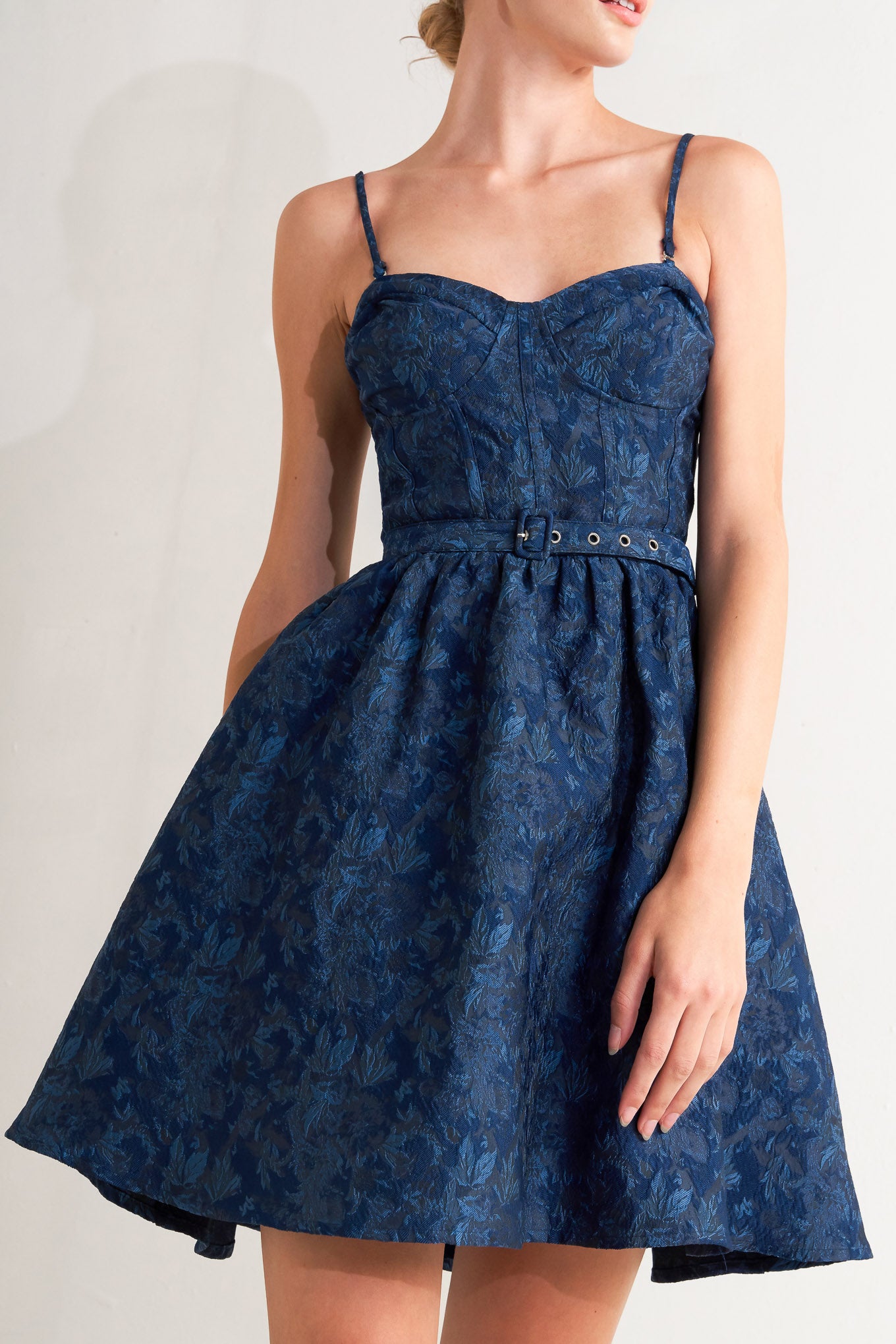 A woven jacquard mini dress featuring bustier top, straps, self belt, full skirt and back zipper closure