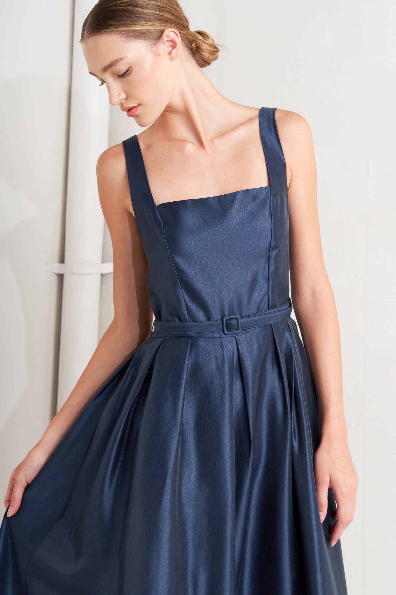 A solid woven midi dress featuring straight neckline, sleeveless, self belt, full skirt and back zipper closure