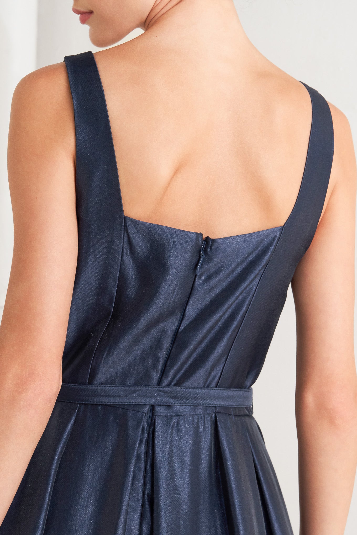 A solid woven midi dress featuring straight neckline, sleeveless, self belt, full skirt and back zipper closure