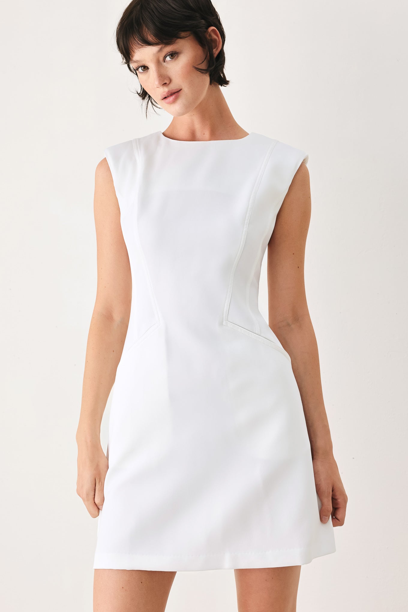 Woman wearing a white shift mini dress featuring wide round neckline, cap sleeve, pockets and back zipper closure | FREEMARKET