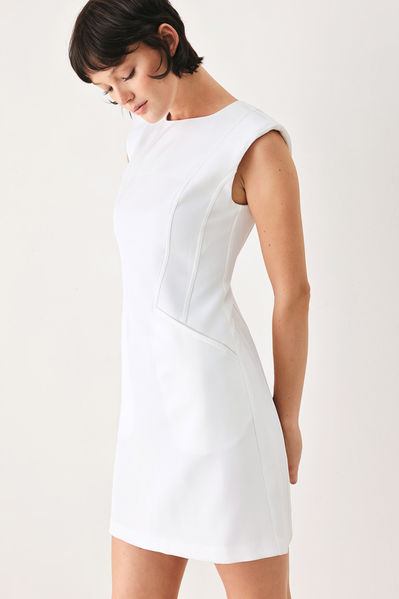 Woman wearing a white shift mini dress featuring wide round neckline, cap sleeve, pockets and back zipper closure | FREEMARKET