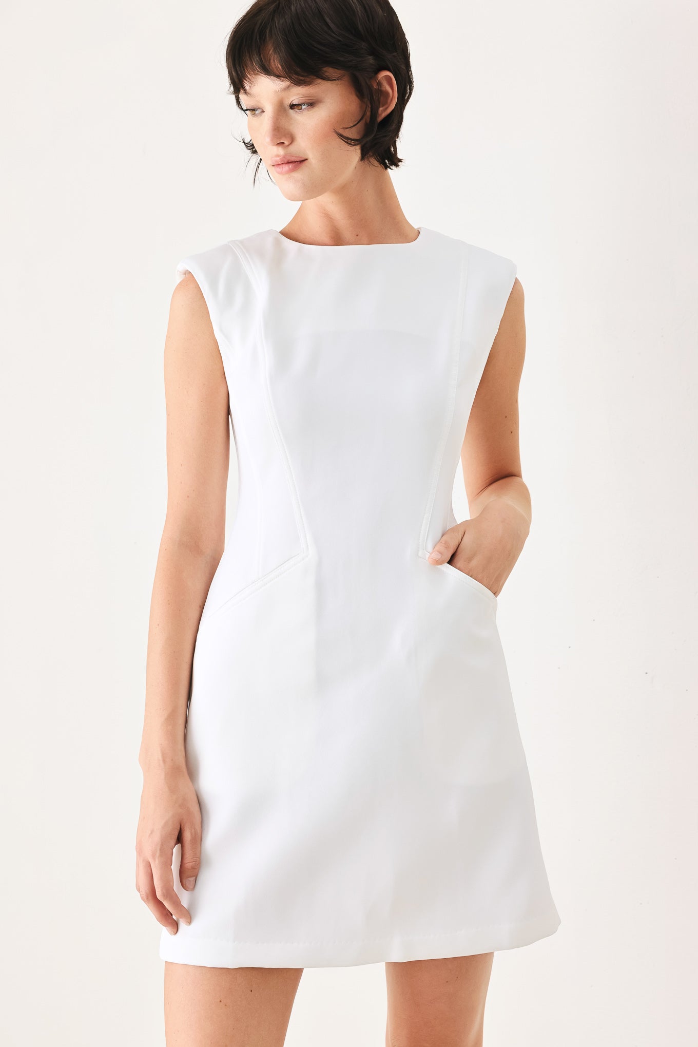 Woman wearing a white shift mini dress featuring wide round neckline, cap sleeve, pockets and back zipper closure | FREEMARKET