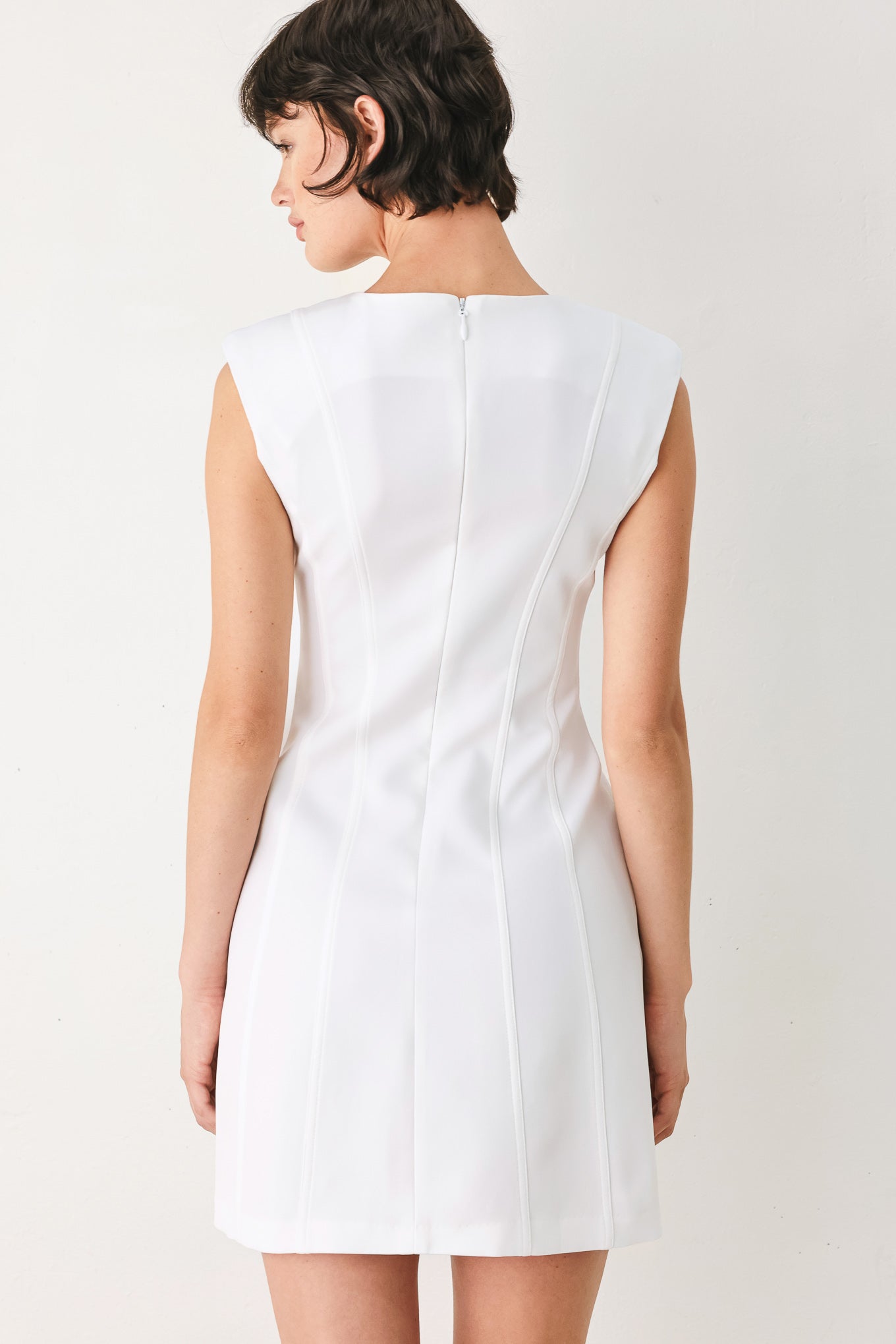 Woman wearing a white shift mini dress featuring wide round neckline, cap sleeve, pockets and back zipper closure | FREEMARKET