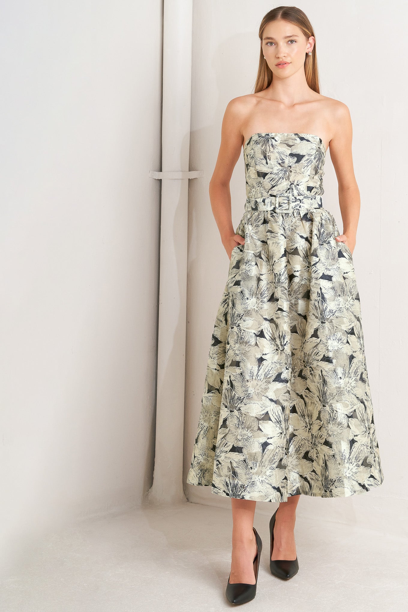 A textured woven midi dress featuring strapless, self belt, full skirt and back zipper closure