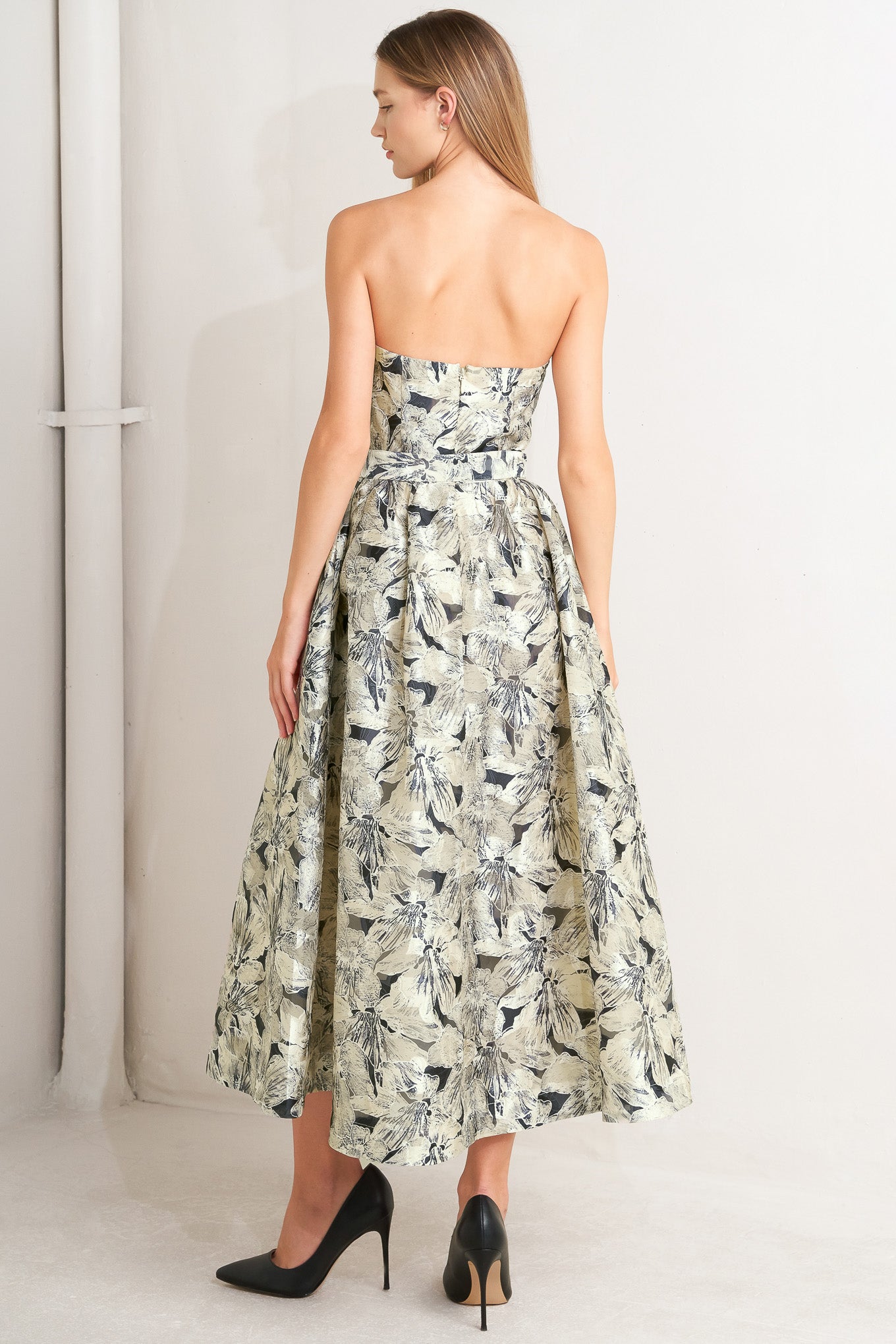 A textured woven midi dress featuring strapless, self belt, full skirt and back zipper closure