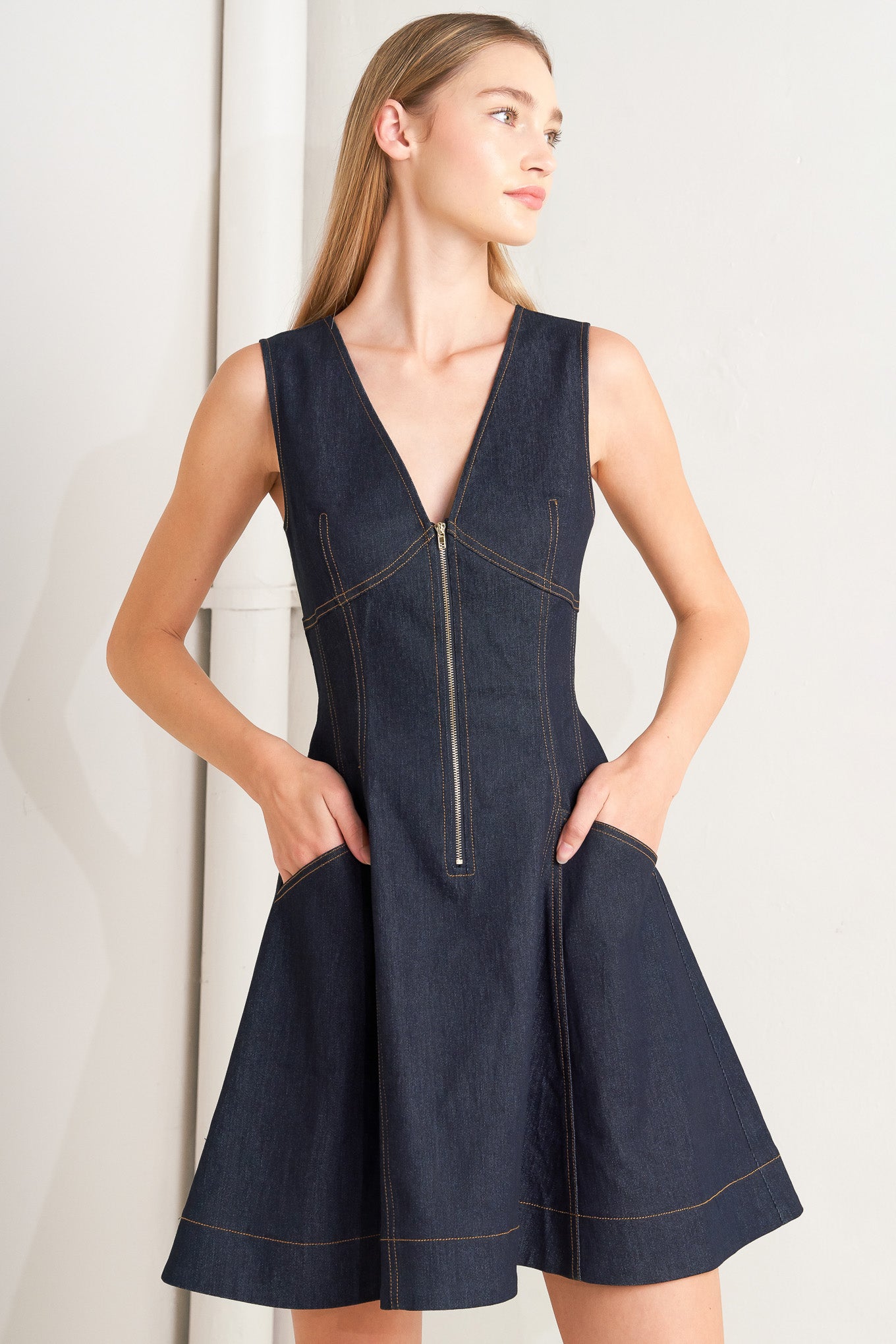 A denim mini dress featuring V neckline, sleeveless, front zipper closure and circle skirt