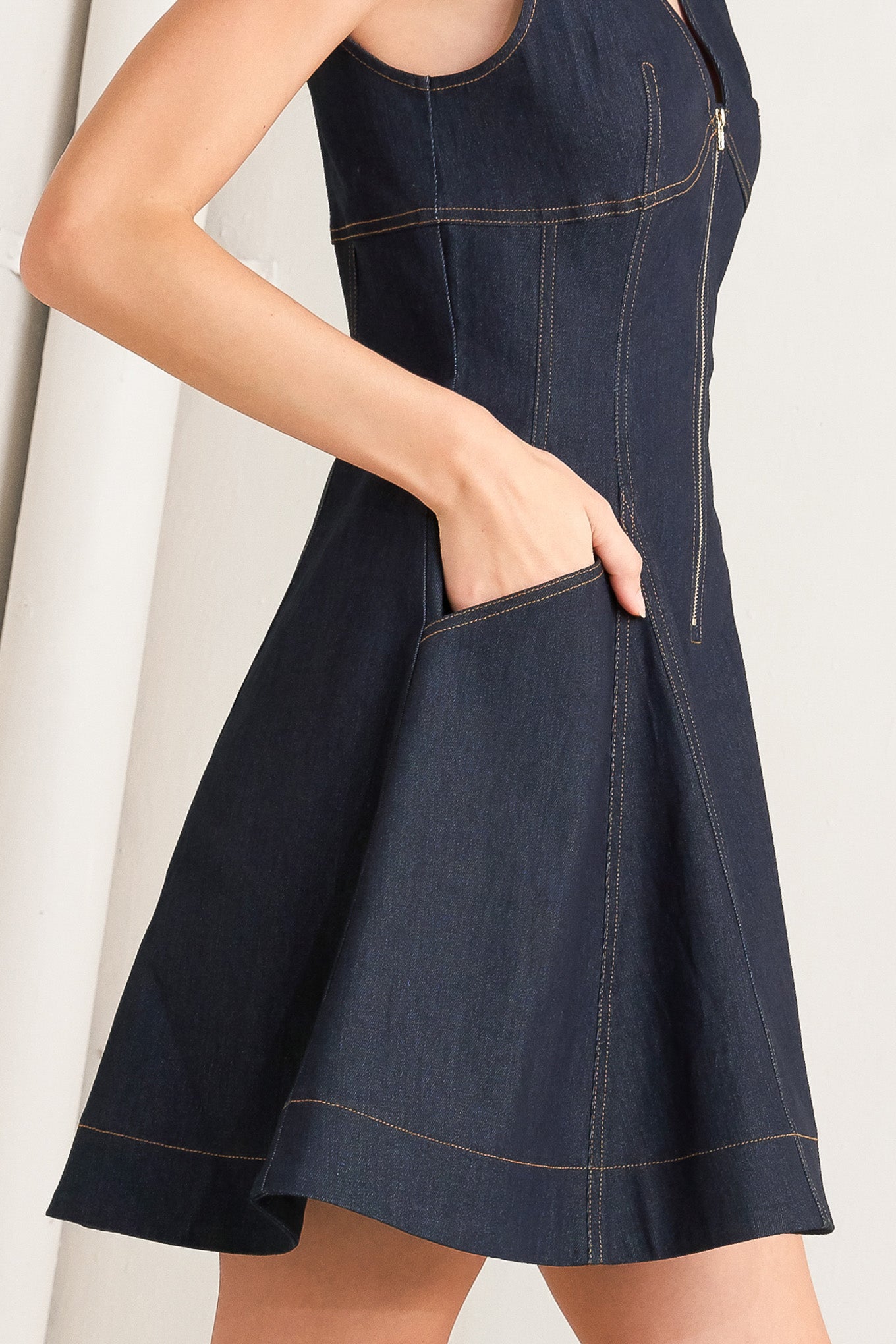 A denim mini dress featuring V neckline, sleeveless, front zipper closure and circle skirt