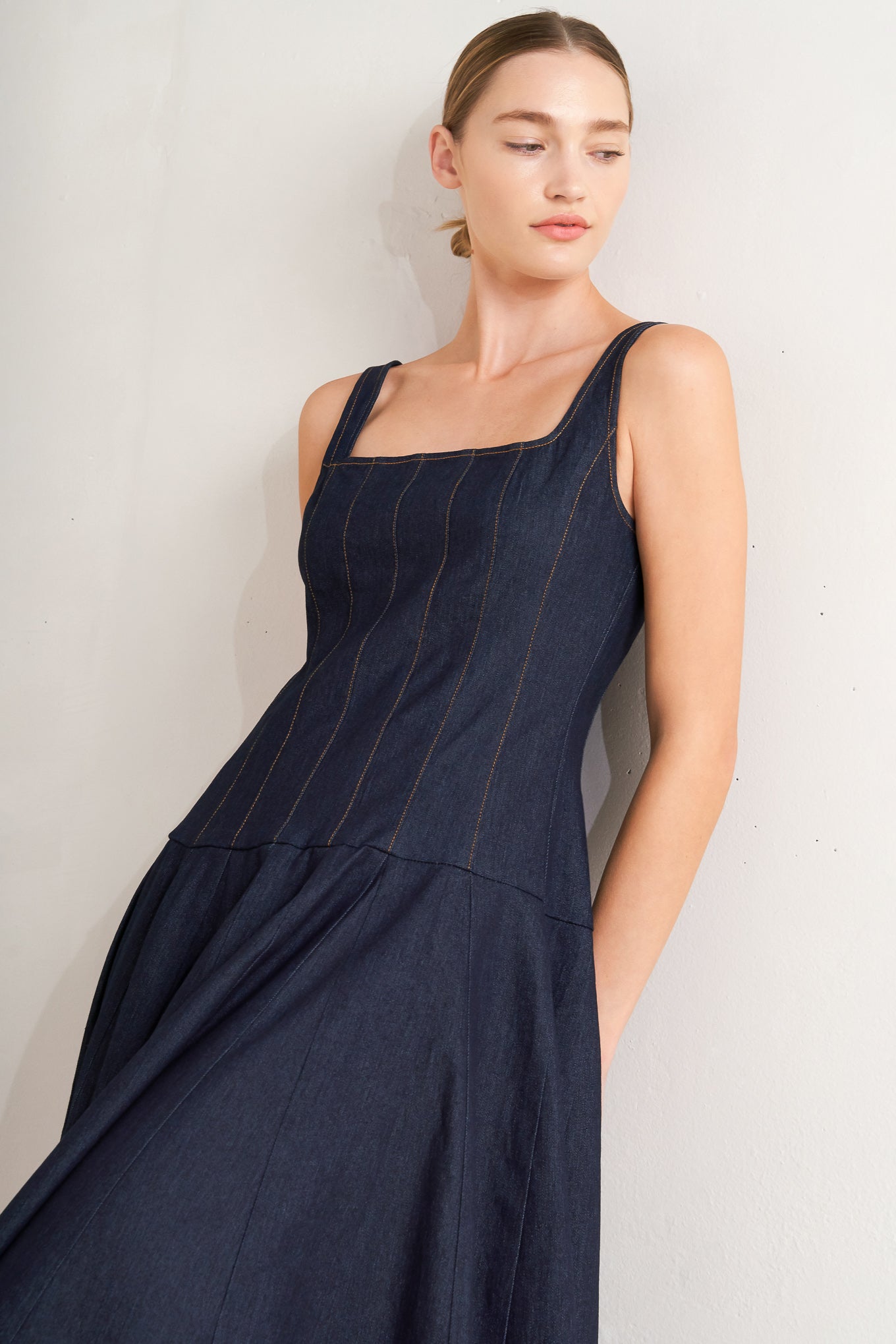 A denim midi dress featuring square neckline, sleeveless, dropped waistline, circle skirt and back zipper closure