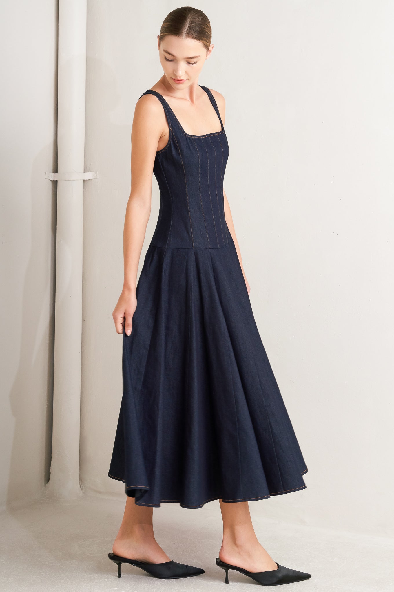 A denim midi dress featuring square neckline, sleeveless, dropped waistline, circle skirt and back zipper closure