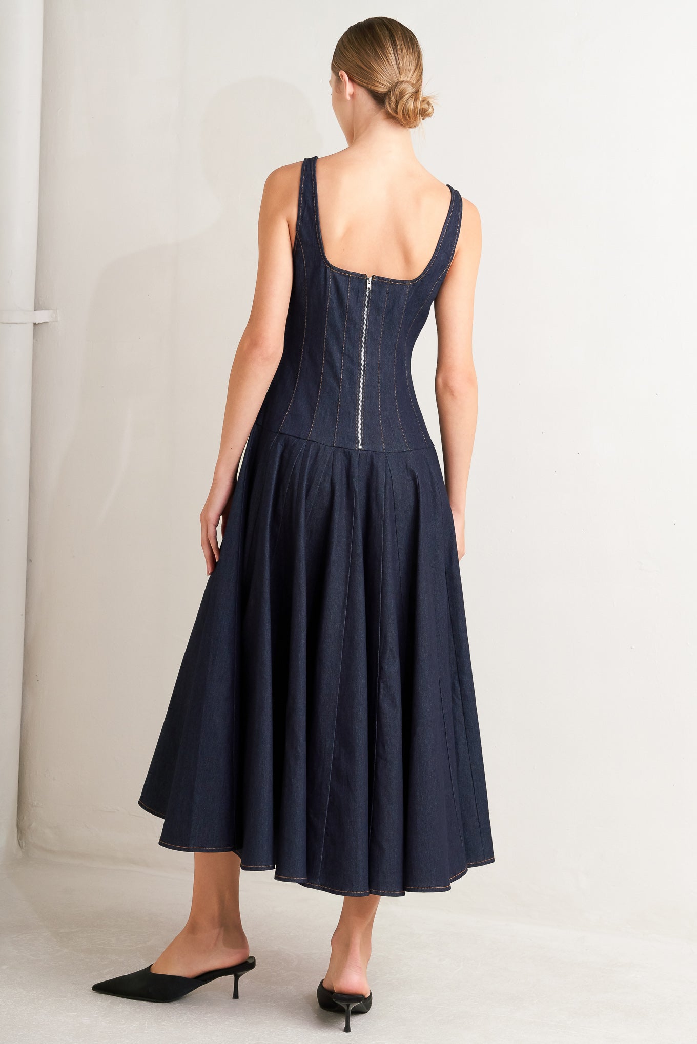 A denim midi dress featuring square neckline, sleeveless, dropped waistline, circle skirt and back zipper closure