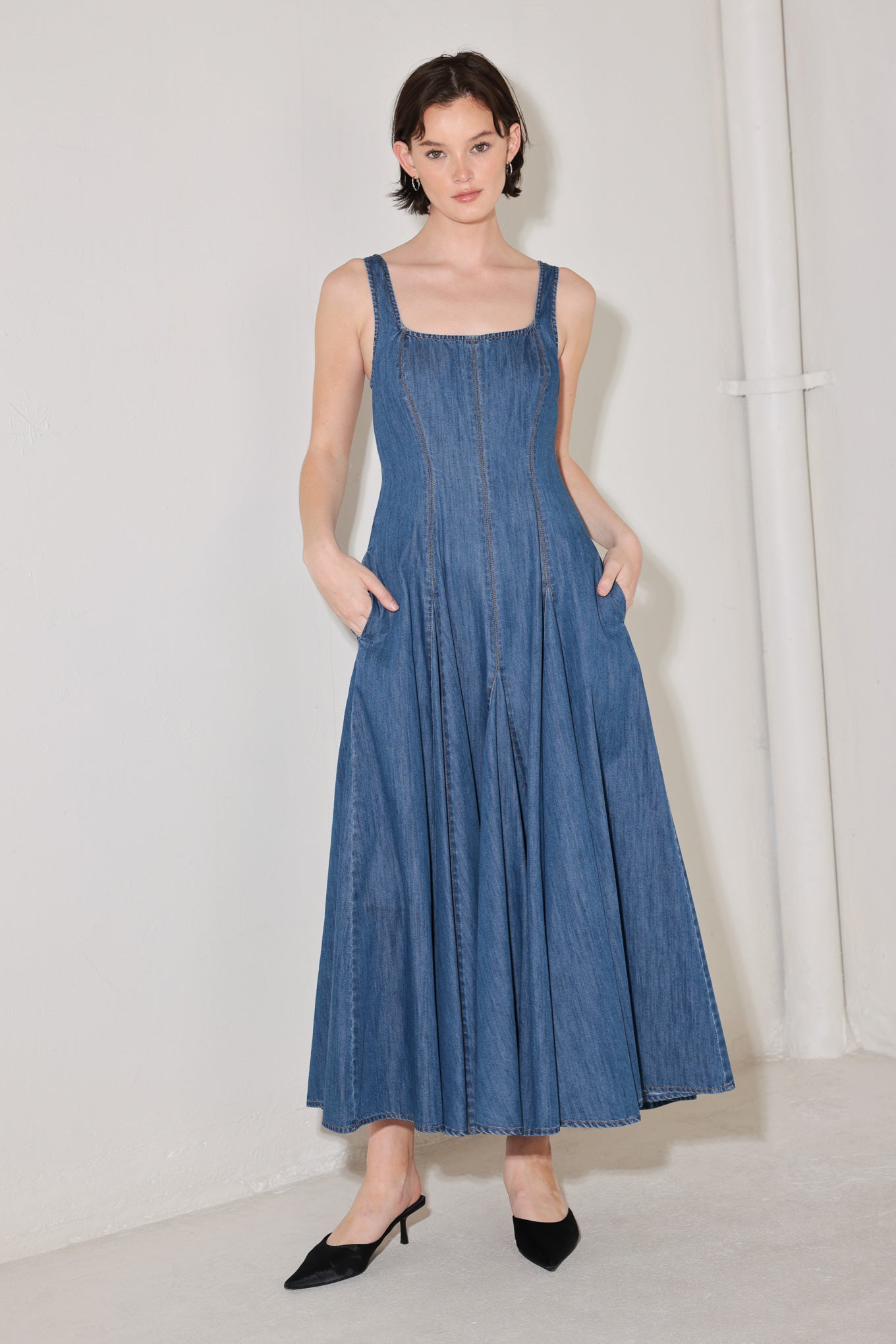 Woman wearing a blue sleeveless denim midi dress featuring square neckline, circle skirt and low back with zipper closure | FREEMARKET | Flying Tomato