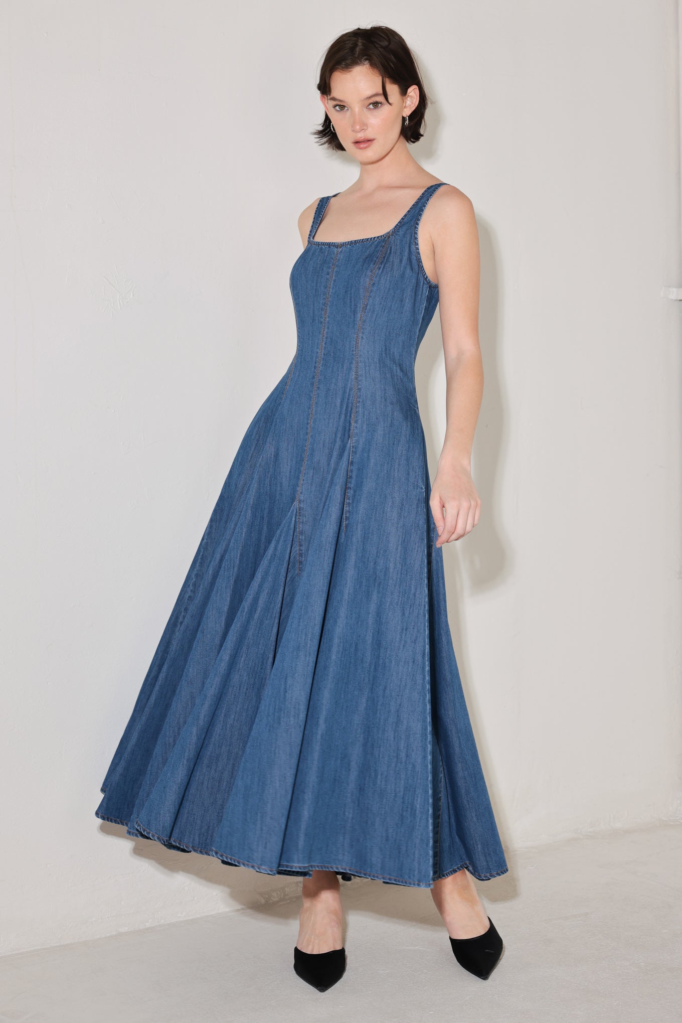 Woman wearing a blue sleeveless denim midi dress featuring square neckline, circle skirt and low back with zipper closure | FREEMARKET | Flying Tomato