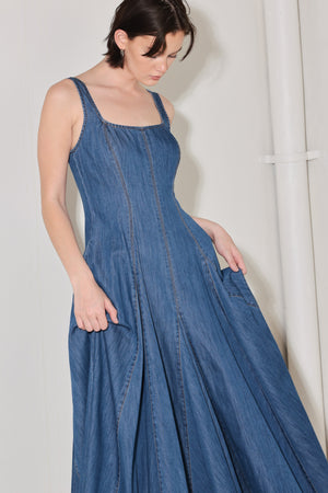 Woman wearing a blue sleeveless denim midi dress featuring square neckline, circle skirt and low back with zipper closure | FREEMARKET | Flying Tomato