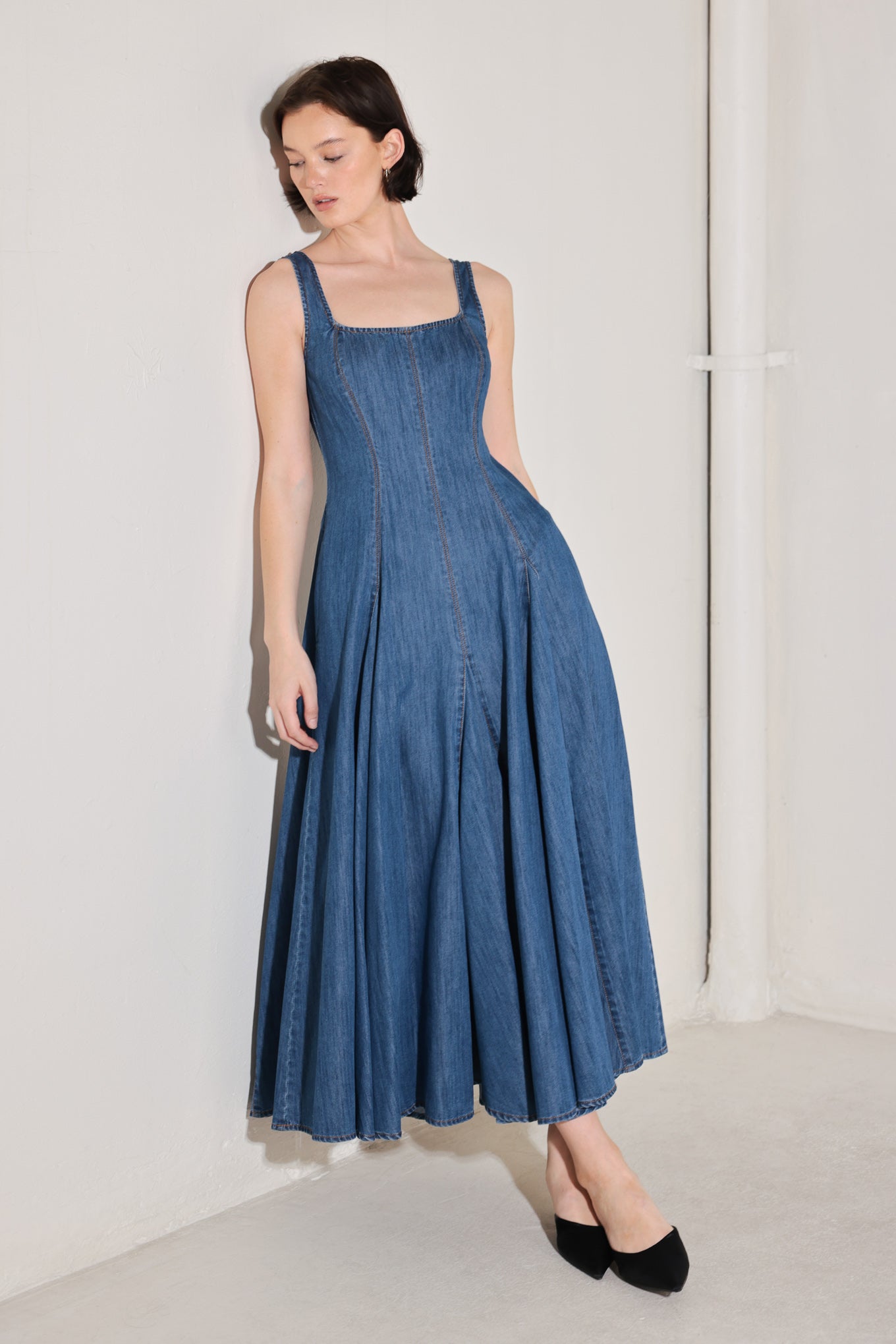 Woman wearing a blue sleeveless denim midi dress featuring square neckline, circle skirt and low back with zipper closure | FREEMARKET | Flying Tomato