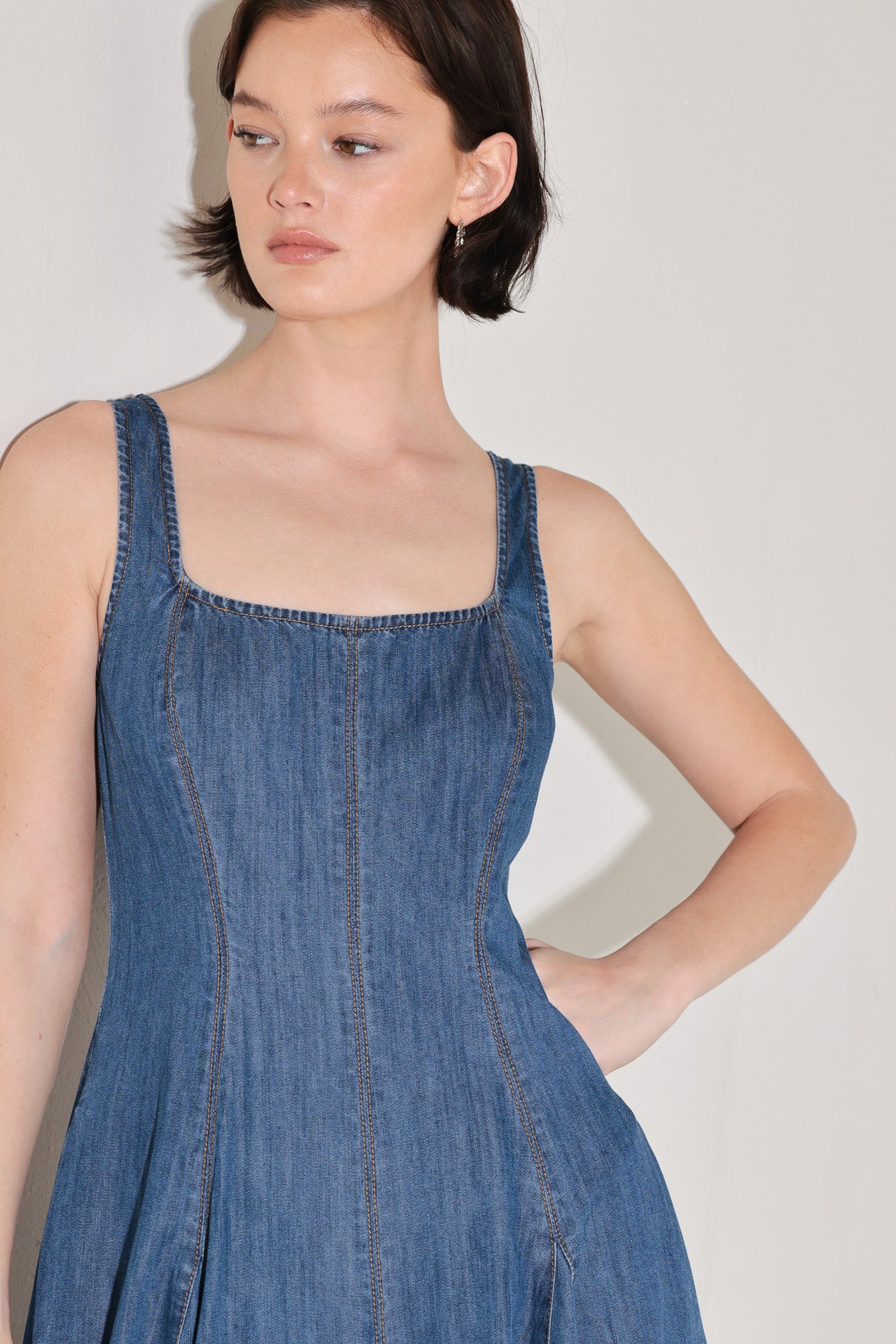 Woman wearing a blue sleeveless denim midi dress featuring square neckline, circle skirt and low back with zipper closure | FREEMARKET | Flying Tomato