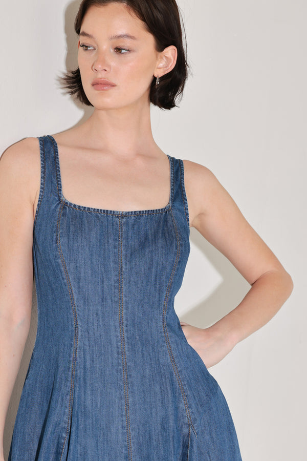 Woman wearing a blue sleeveless denim midi dress featuring square neckline, circle skirt and low back with zipper closure | FREEMARKET | Flying Tomato
