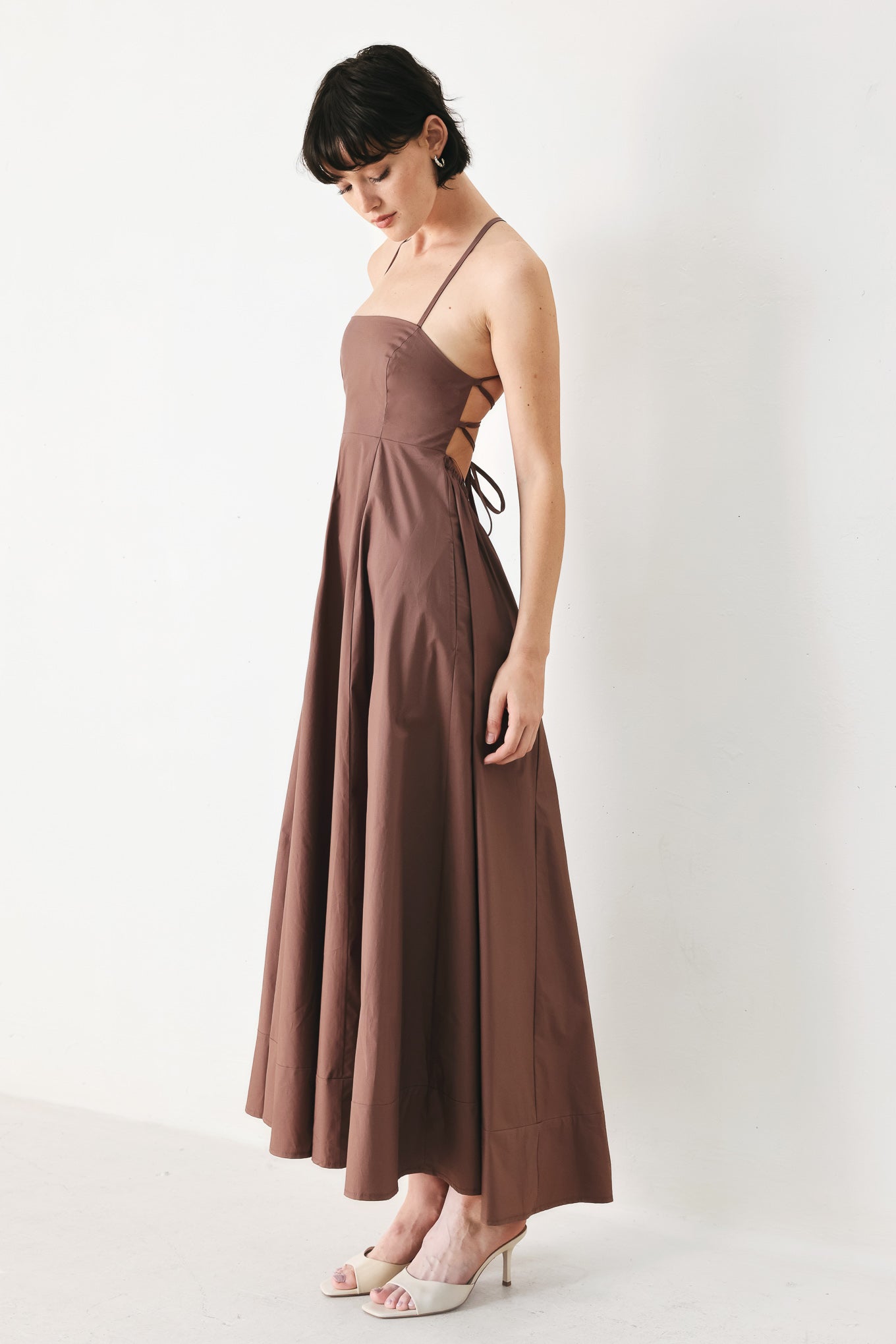 Woman wearing a brown midi dress featuring straight neckline, circle skirt and bare back with lace up tie closure | FREEMARKET | Flying Tomato