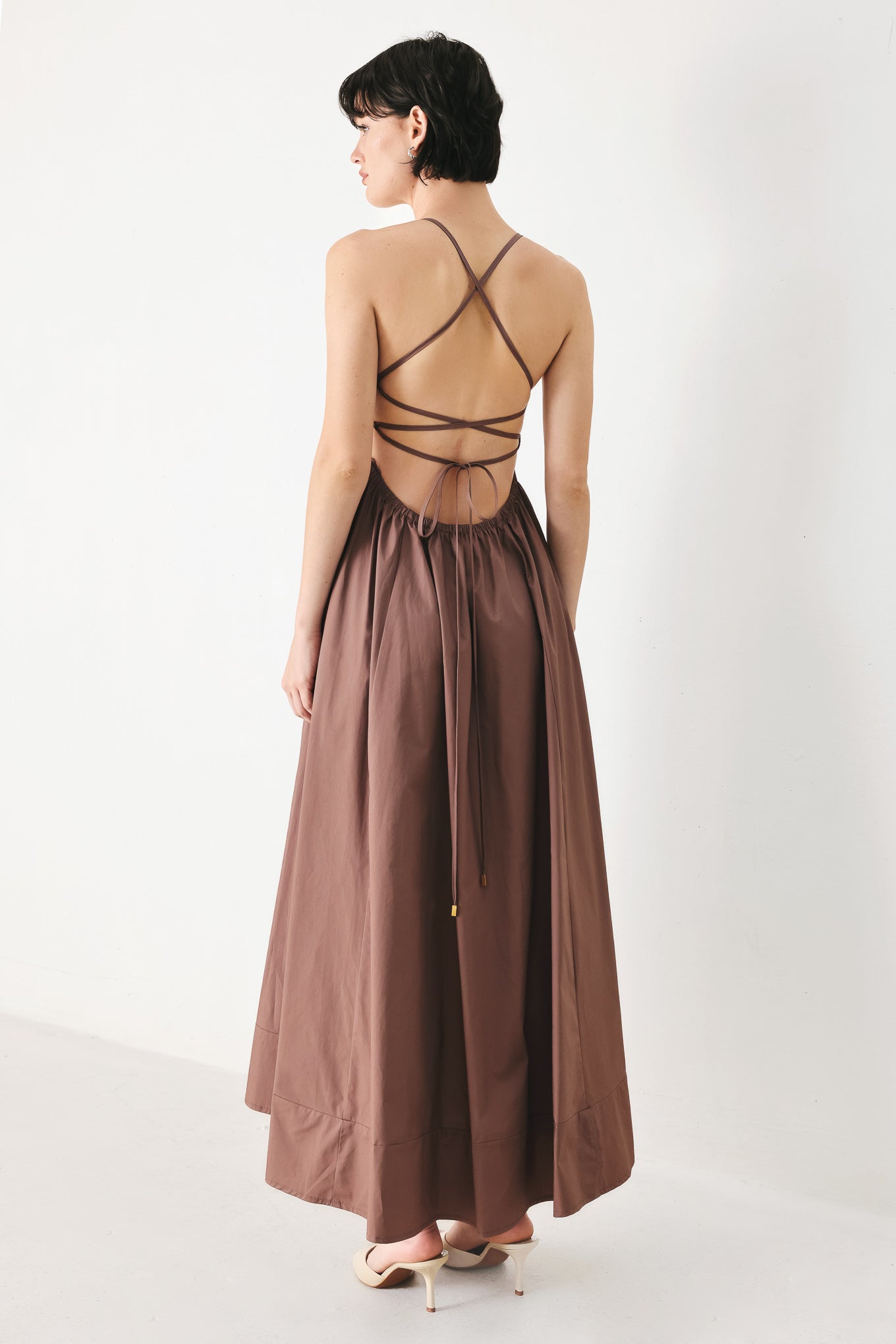 Woman wearing a brown midi dress featuring straight neckline, circle skirt and bare back with lace up tie closure | FREEMARKET | Flying Tomato
