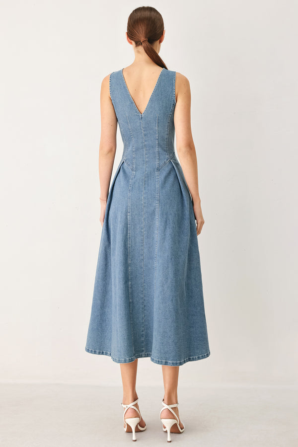 Woman wearing a sleeveless blue denim midi dress with V neckline, button down, and side pleat | FREEMARKET
