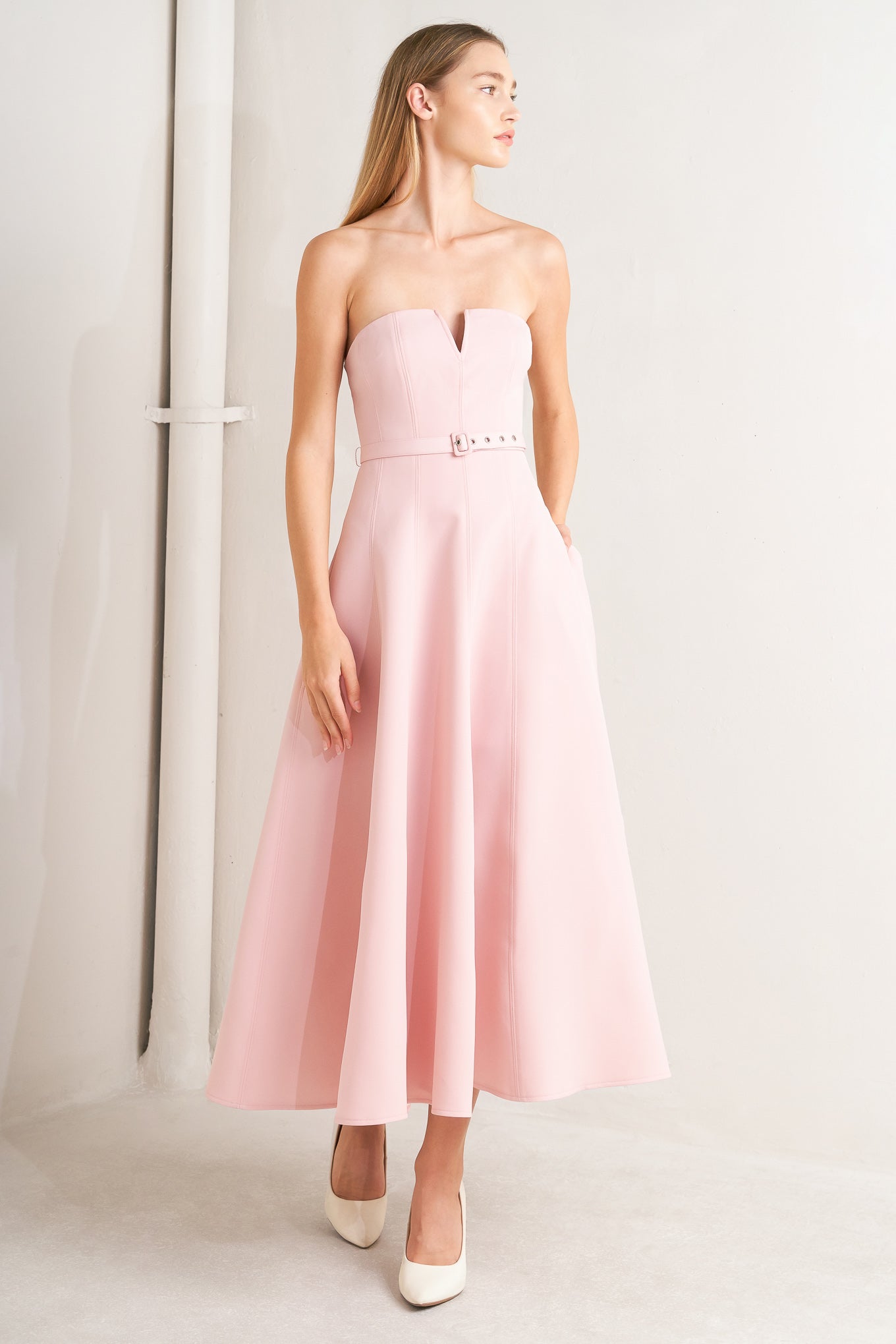 A solid woven midi dress featuring strapless with V front, self belt, circle skirt and back zipper closure