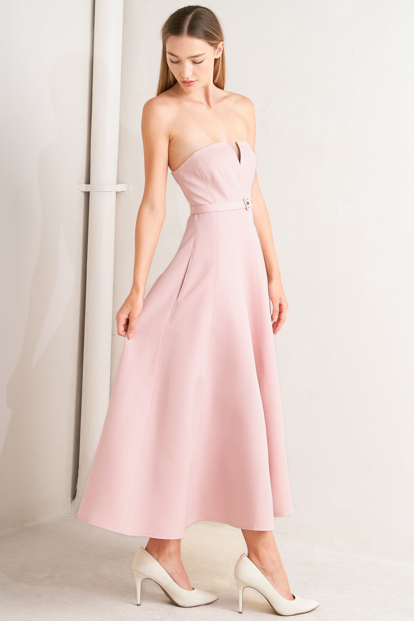 A solid woven midi dress featuring strapless with V front, self belt, circle skirt and back zipper closure