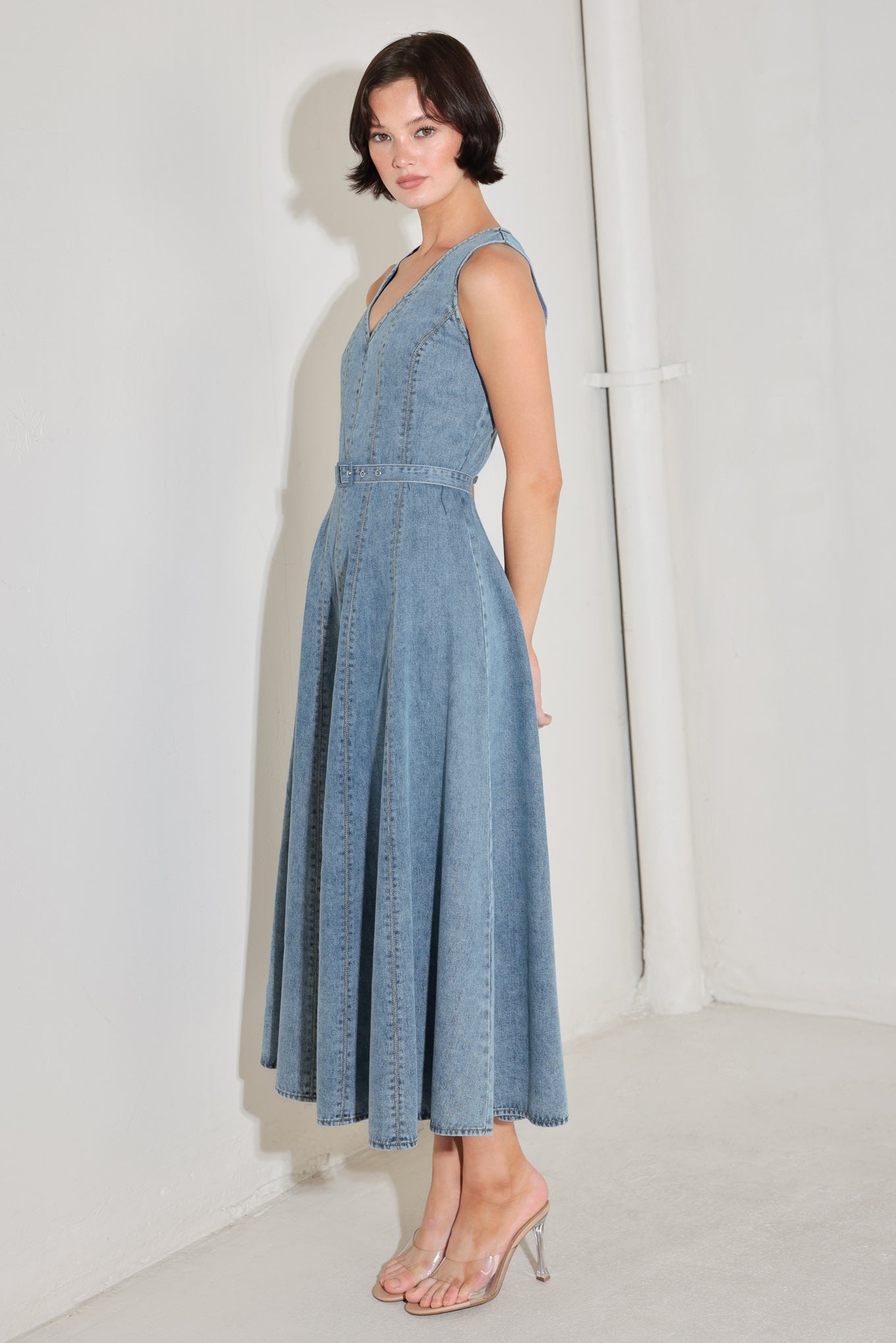 
A washed denim midi dress featuring V neckline, sleeveless, self belt, circle skirt, side pockets and back zipper closure

Details:

Self : 90% Cotton 10% Polyester

Size &amp; Fit

- Model is 5`8" And Wearing Size Small
- Measurements Taken From Size Small
- Approx. Length: 50"