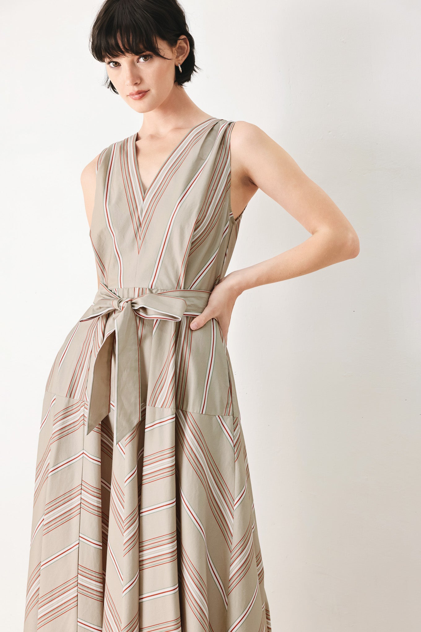 Woman wearing a striped sleeveless woven midi dress featuring V neckline, drop waist, self tie, circle skirt and back zipper closure | FREEMARKET
