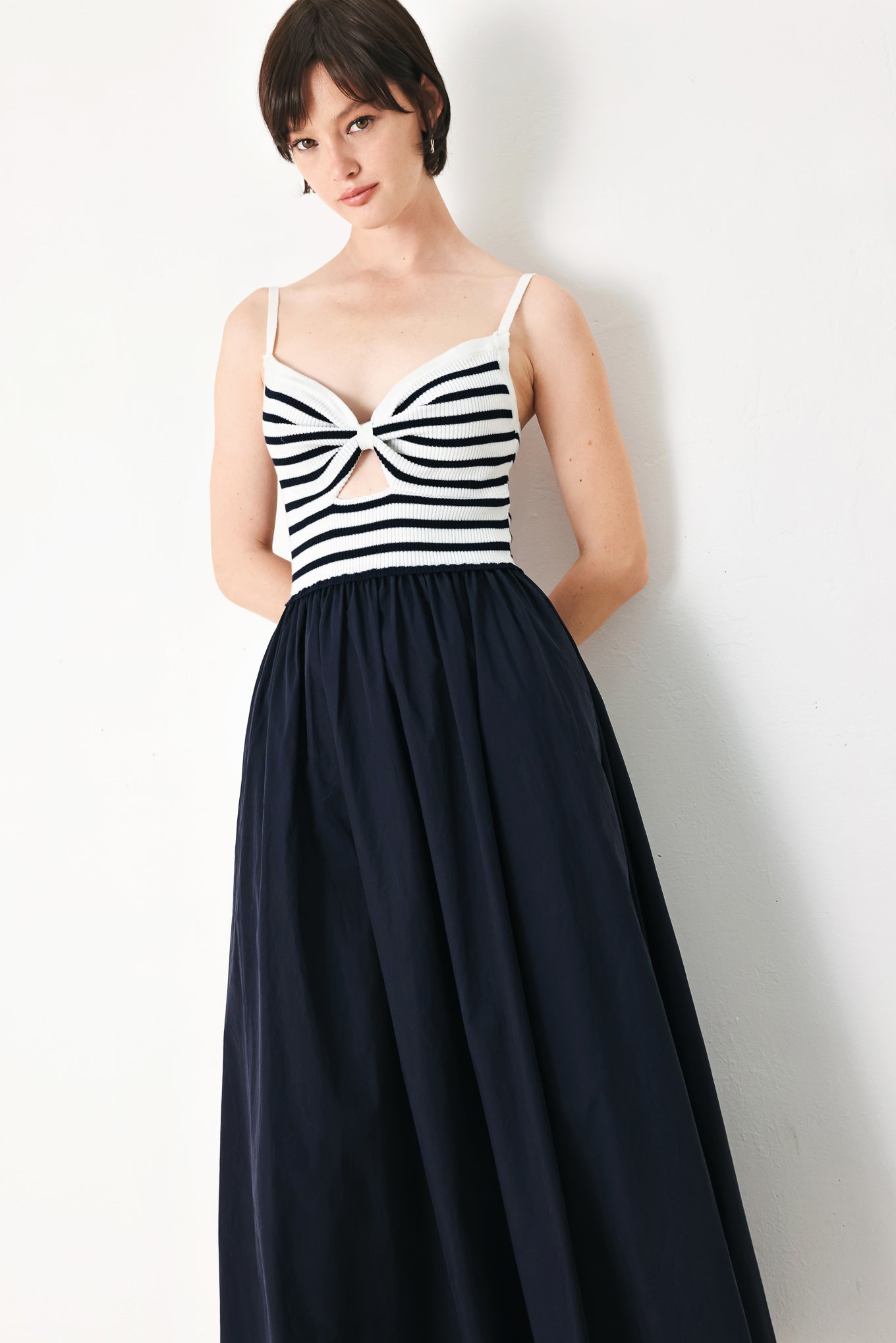 A midi dress featuring sweater knit top with cinched front bodice and cut out, straps and solid woven full skirt