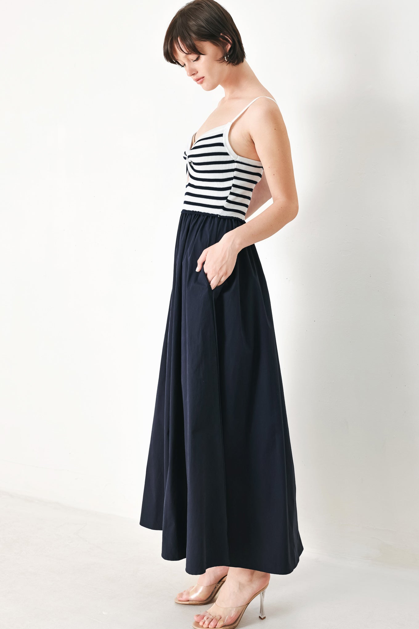 A midi dress featuring sweater knit top with cinched front bodice and cut out, straps and solid woven full skirt