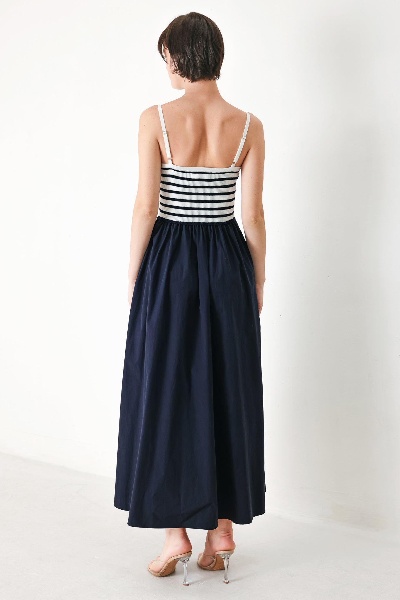 A midi dress featuring sweater knit top with cinched front bodice and cut out, straps and solid woven full skirt