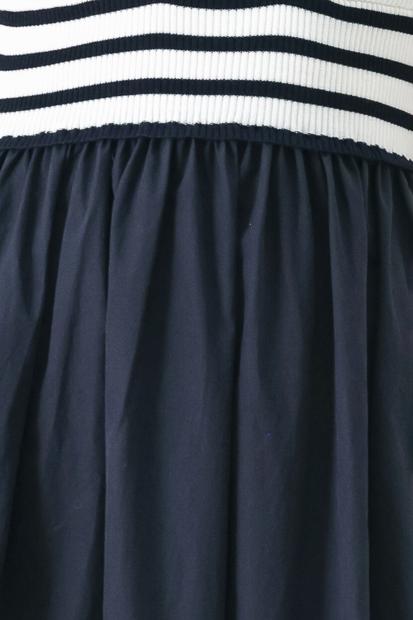 A midi dress featuring sweater knit top with cinched front bodice and cut out, straps and solid woven full skirt