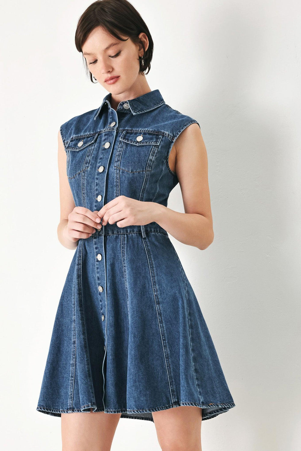 A washed denim mini dress featuring collar, short sleeve, front pockets, front button down and circle skirt