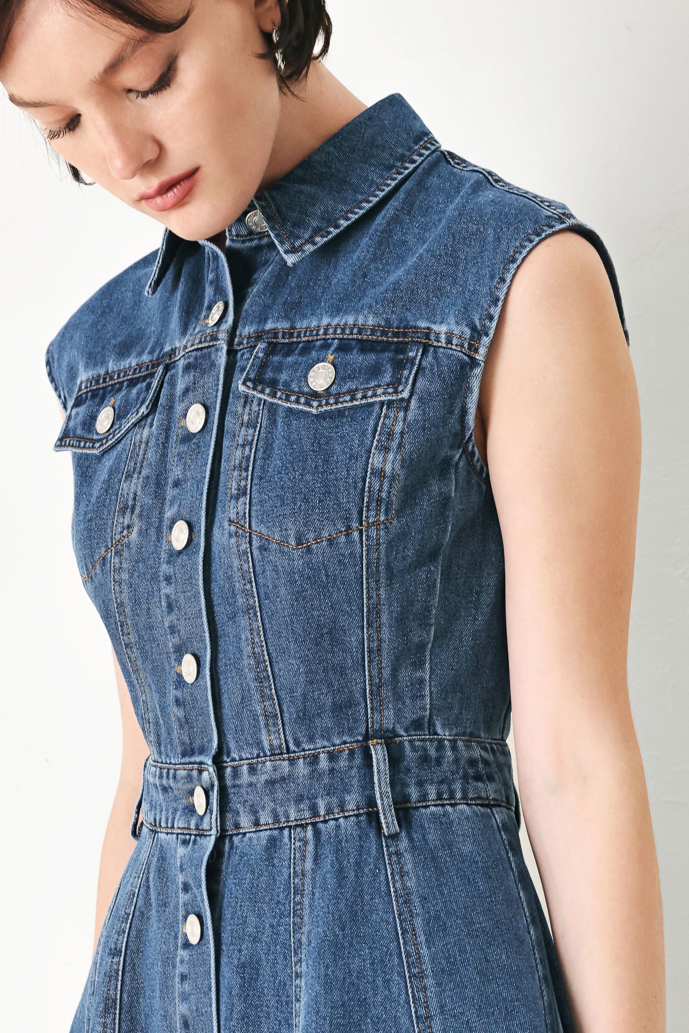 A washed denim mini dress featuring collar, short sleeve, front pockets, front button down and circle skirt