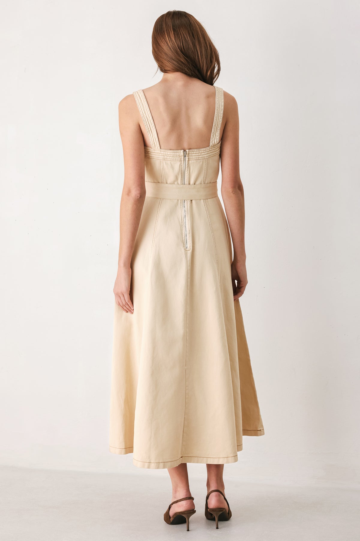 A woman modeling a sleeveless midi dress in a light beige or neutral color, featuring a square neckline, a matching belt at the waist, and a flared skirt | FREEMARKET