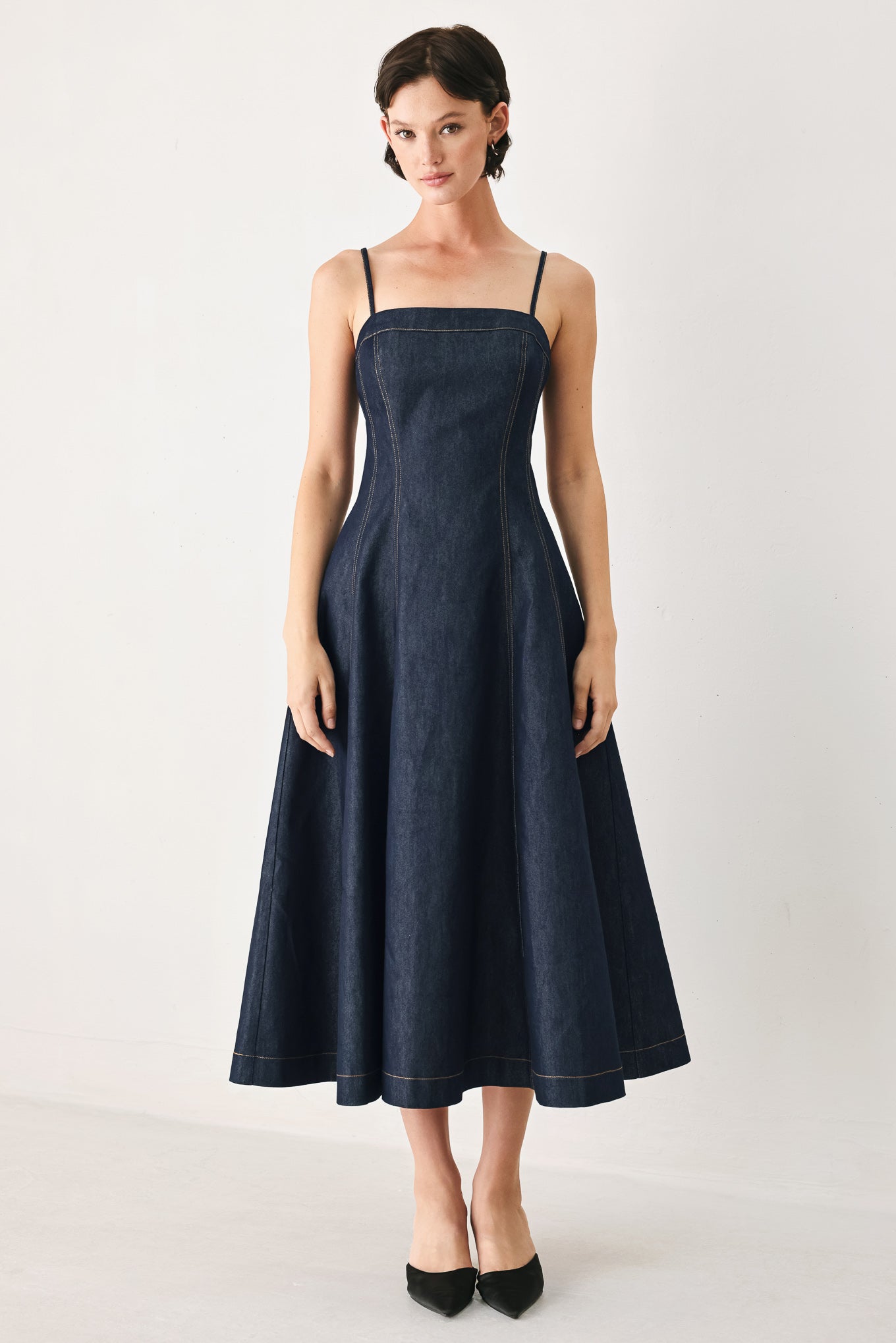 Woman wearing a navy blue denim midi dress with straight neckline, straps, full circle skirt and back zipper closure | FREEMARKET