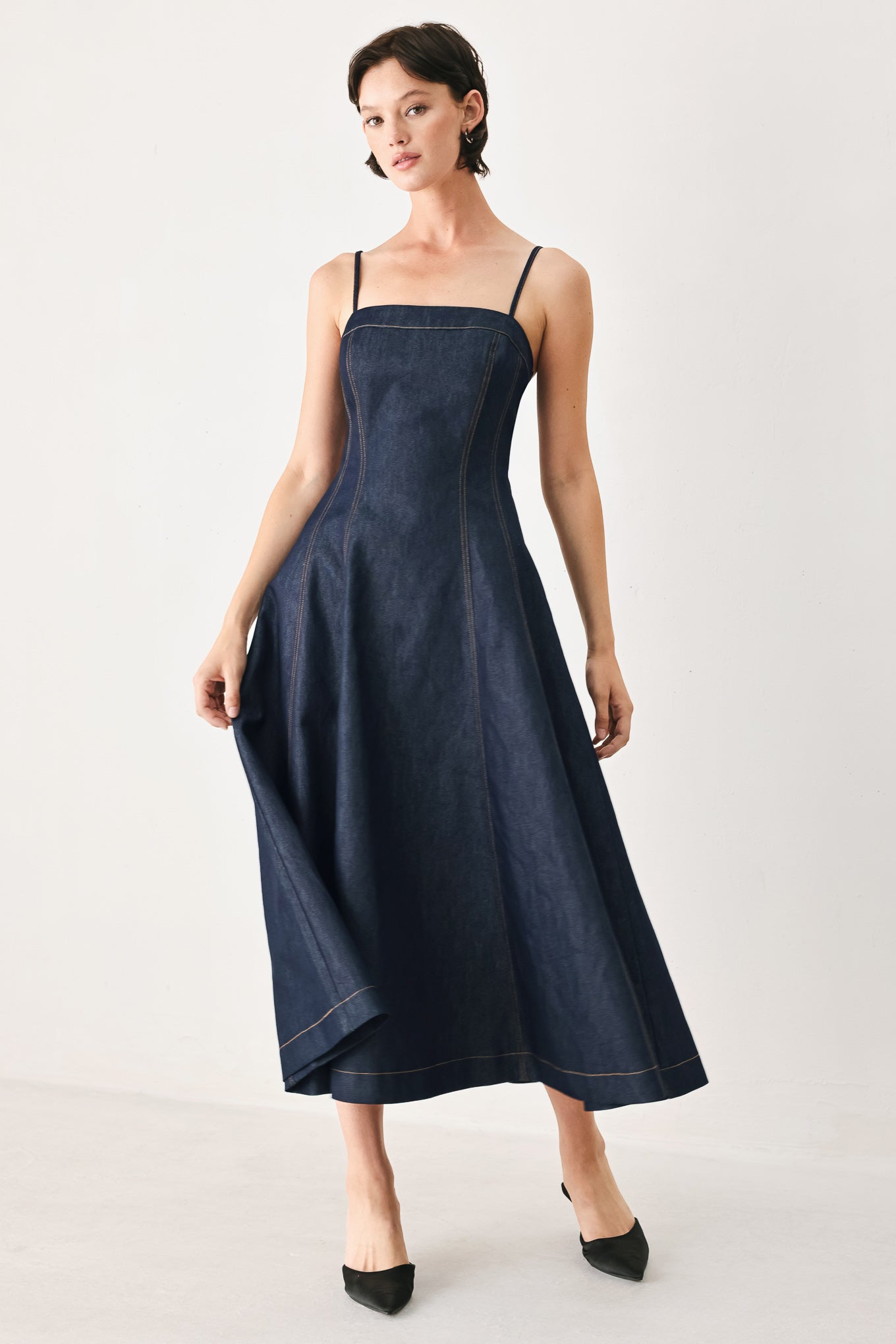 Woman wearing a navy blue denim midi dress with straight neckline, straps, full circle skirt and back zipper closure | FREEMARKET