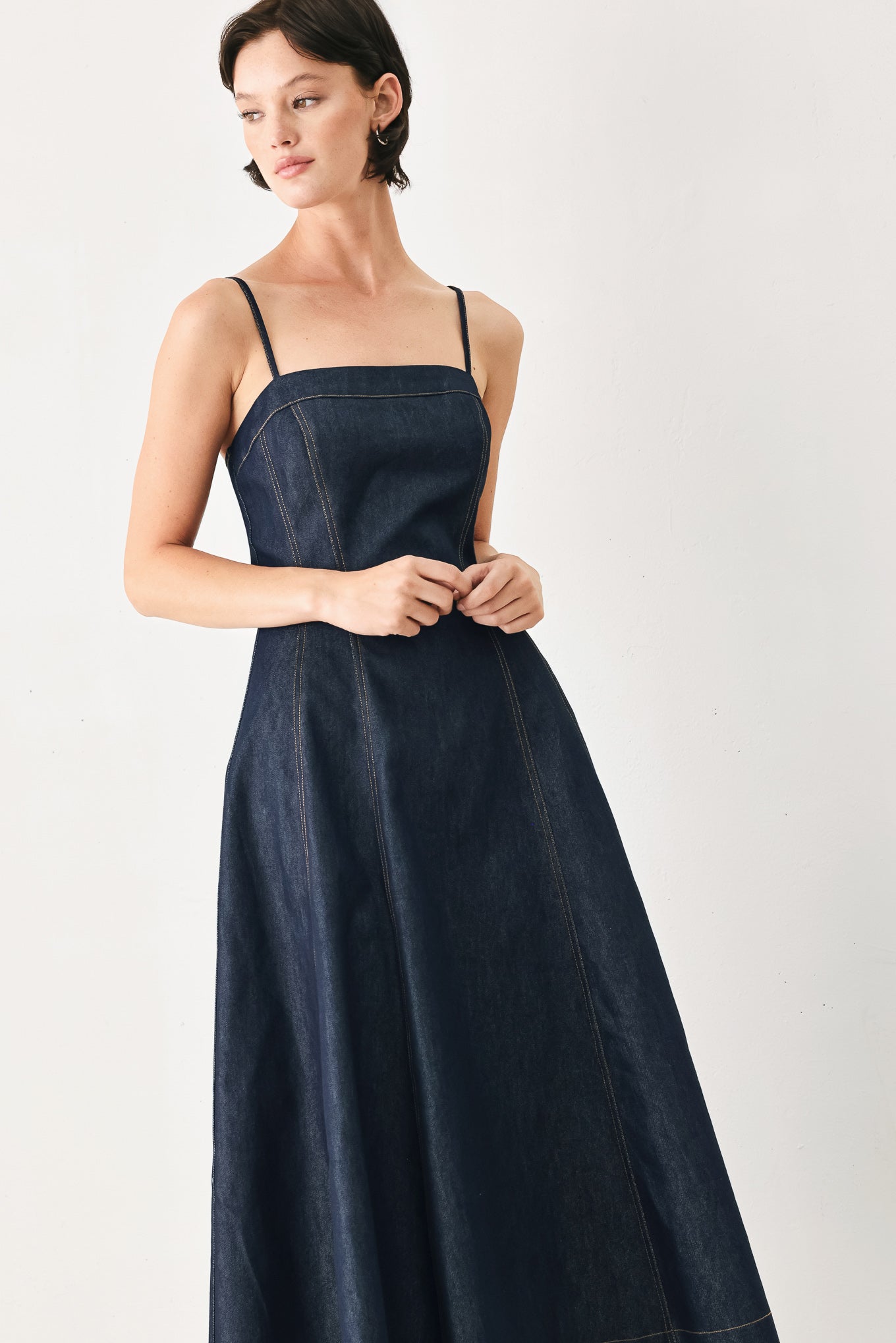 Woman wearing a navy blue denim midi dress with straight neckline, straps, full circle skirt and back zipper closure | FREEMARKET