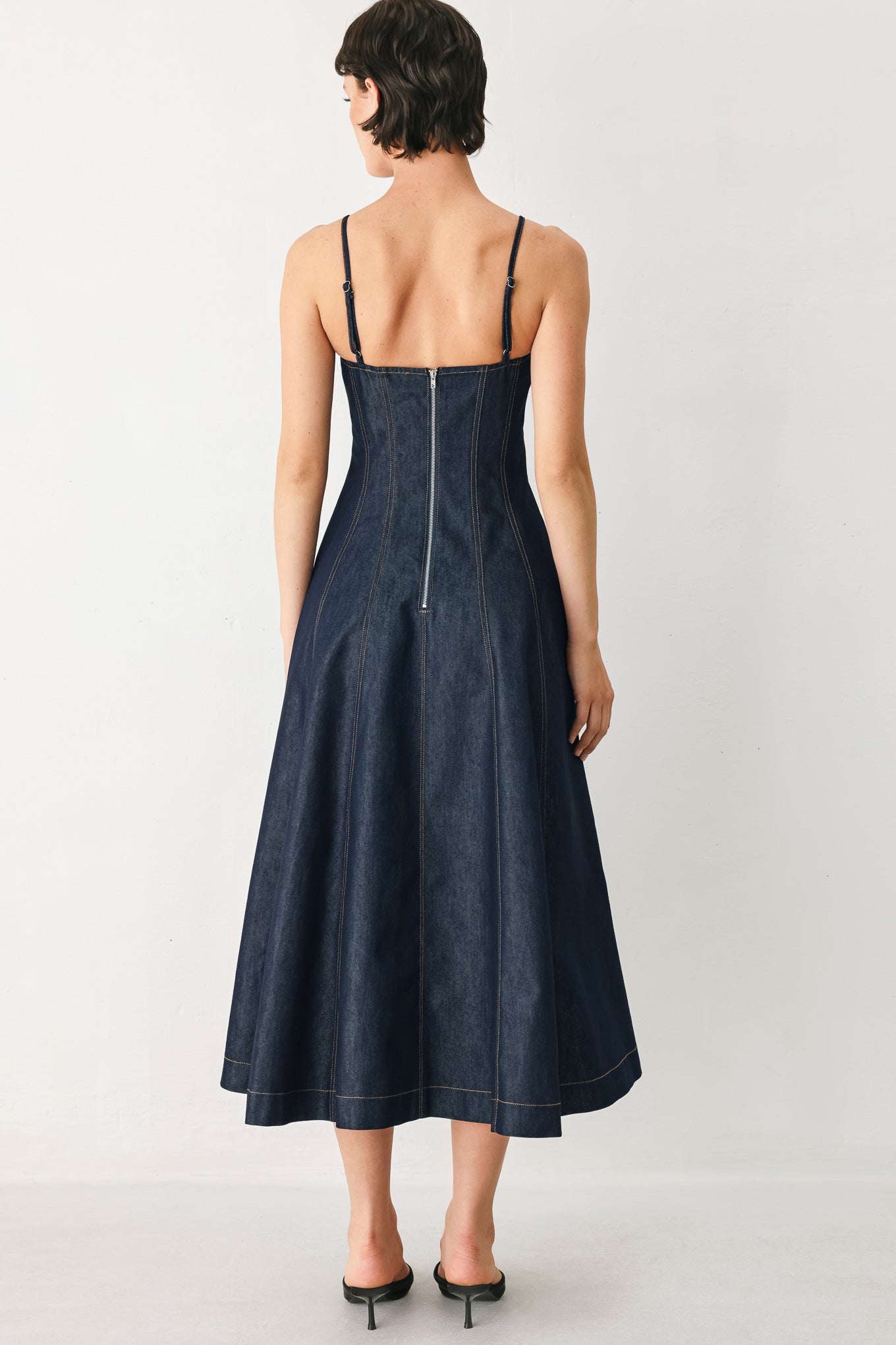Woman wearing a navy blue denim midi dress with straight neckline, straps, full circle skirt and back zipper closure | FREEMARKET